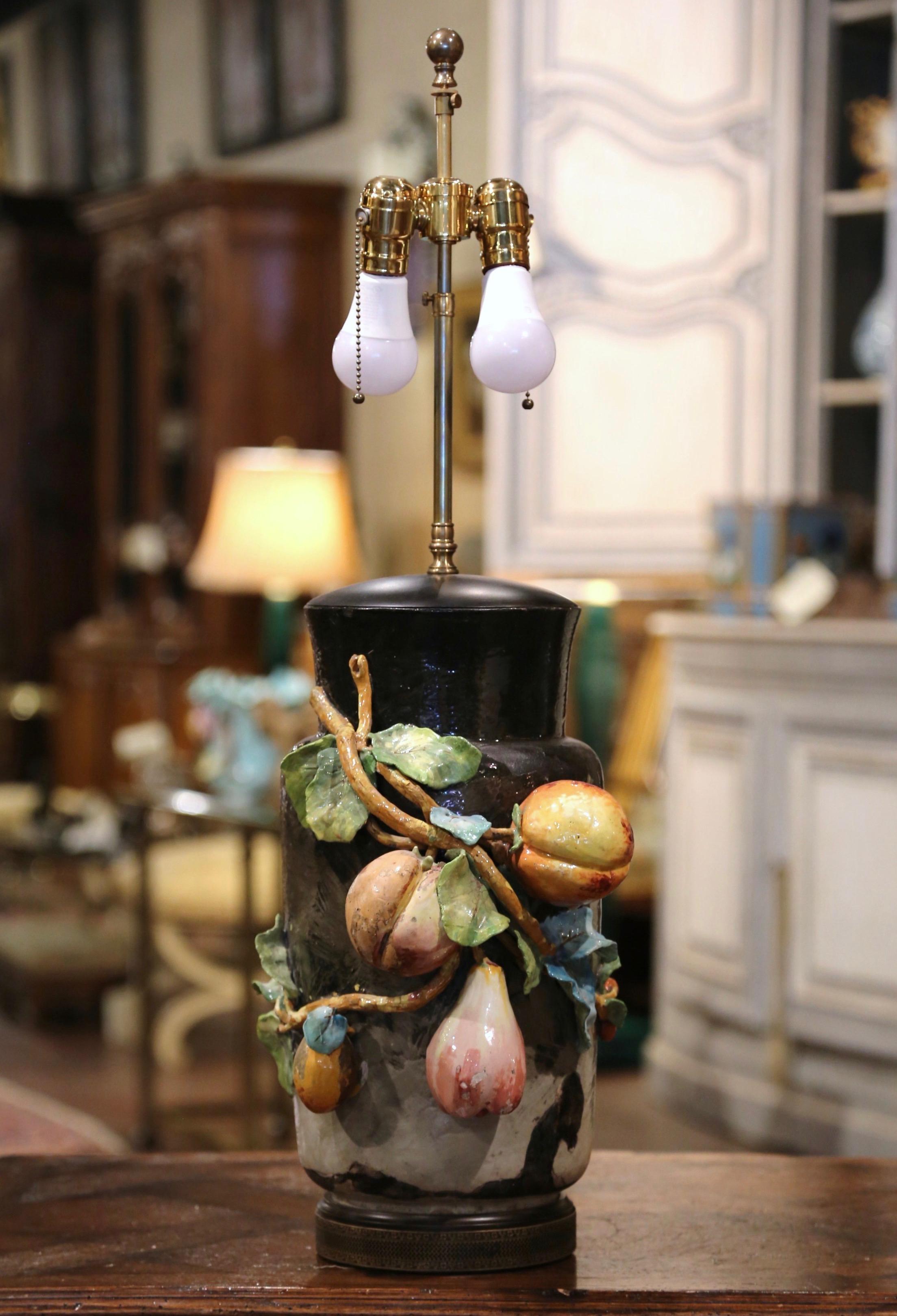 This beautiful, hand painted Majolica vase converted into a table lamp was sculpted in Montigny sur Loing, France, circa 1870. This black, green and grey ceramic vase stands on a wooden base and is decorated with colorful high relief fruit motifs
