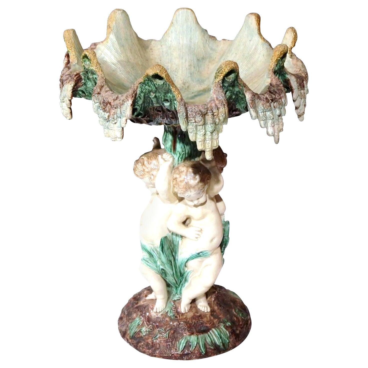Decorate a table or counter top with this colorful antique Majolica centerpiece. Crafted in France, circa 1890 and attributed to Thomas Sergent, the elegant jardinière features a decorative bowl with dripping motif on the sides and three cherubs