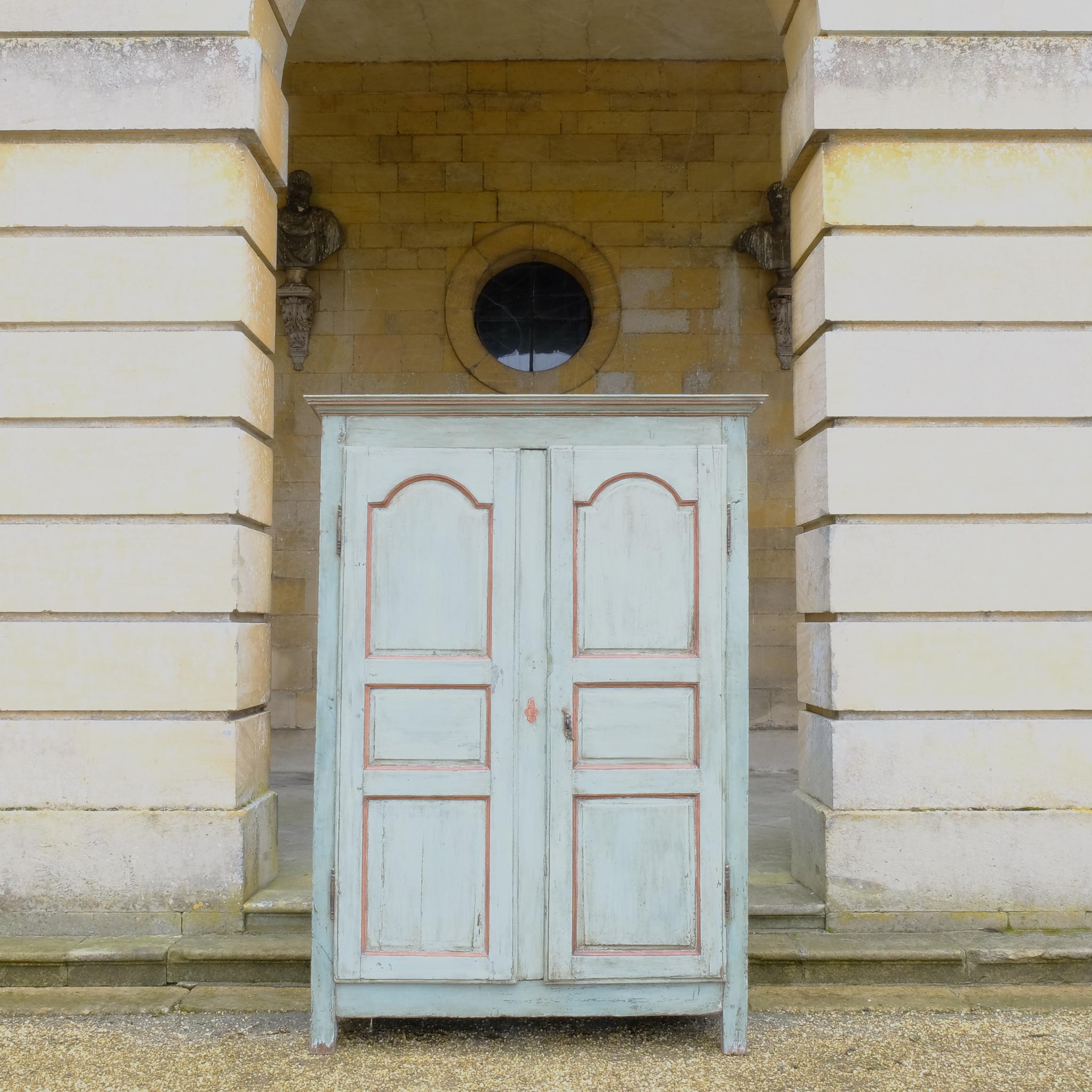 A large 19th century French light blue/green painted cupboard. A moulded cornice above panelled doors with decorative iron hinges and single escutcheon with key. A beautiful colour combination, with a charming crackled patina throughout. Fitted with