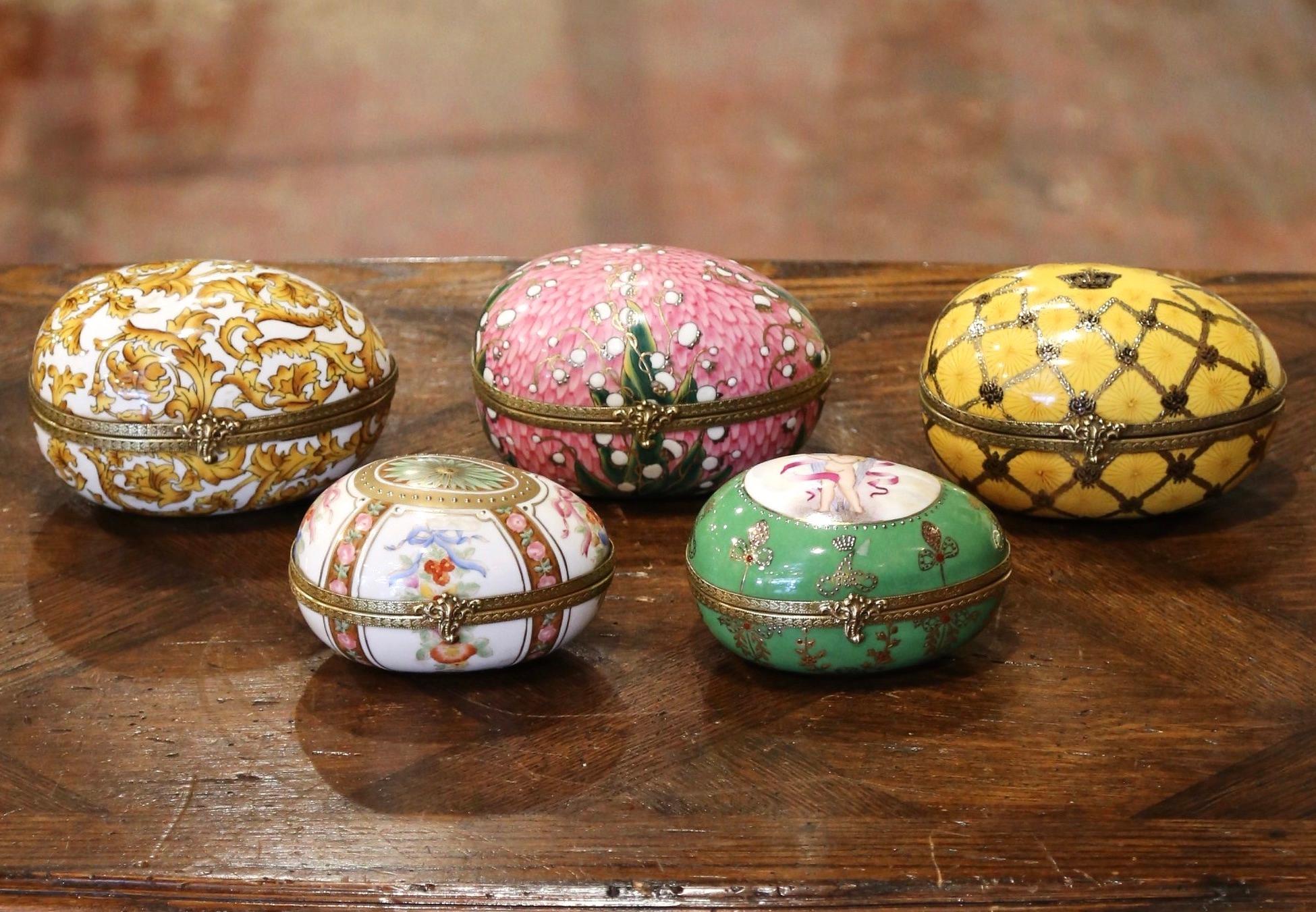 Decorate a shelf with this elegant set of antique porcelain egg boxes. Crafted in Limoges France circa 1880, each colorful porcelain piece is dressed with a decorative brass rim with back hinge and locking mechanism; each egg features hand painted