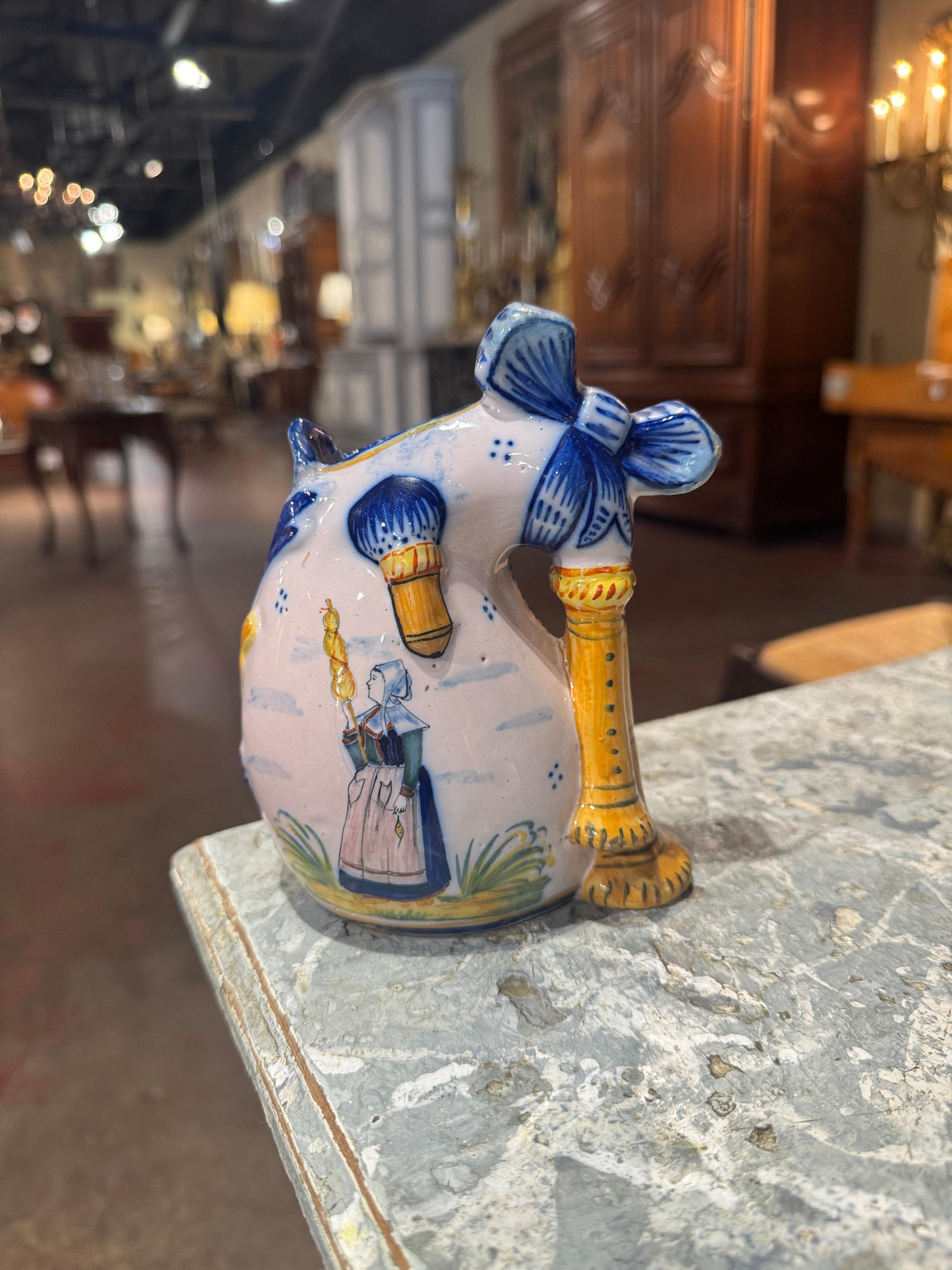 Décorez un mur de cuisine ou une étagère avec cet élégant vase décoratif antique. Créé à Quimper, en France, vers 1890, le vase en céramique en forme de coquille de cornemuse, avec un nœud au fronton, est décoré d'une femme bretonne peinte à la main