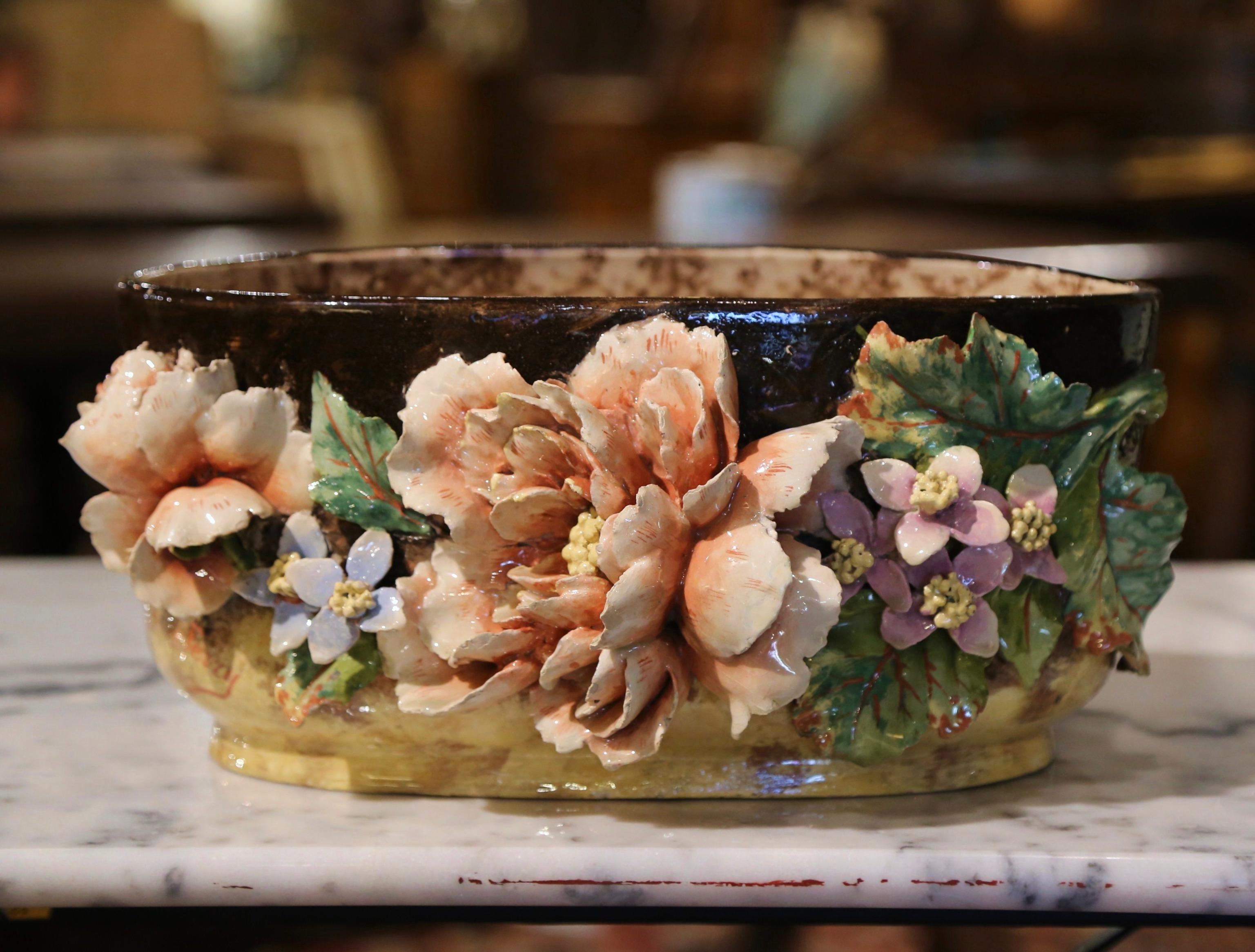 This colorful hand painted Majolica planter was sculpted in Montigny sur Loing, France, circa 1880. Oval in shape, the ceramic jardinière features floral and leaf decor in high relief all around. The colorful flowers are hand painted in the pink,
