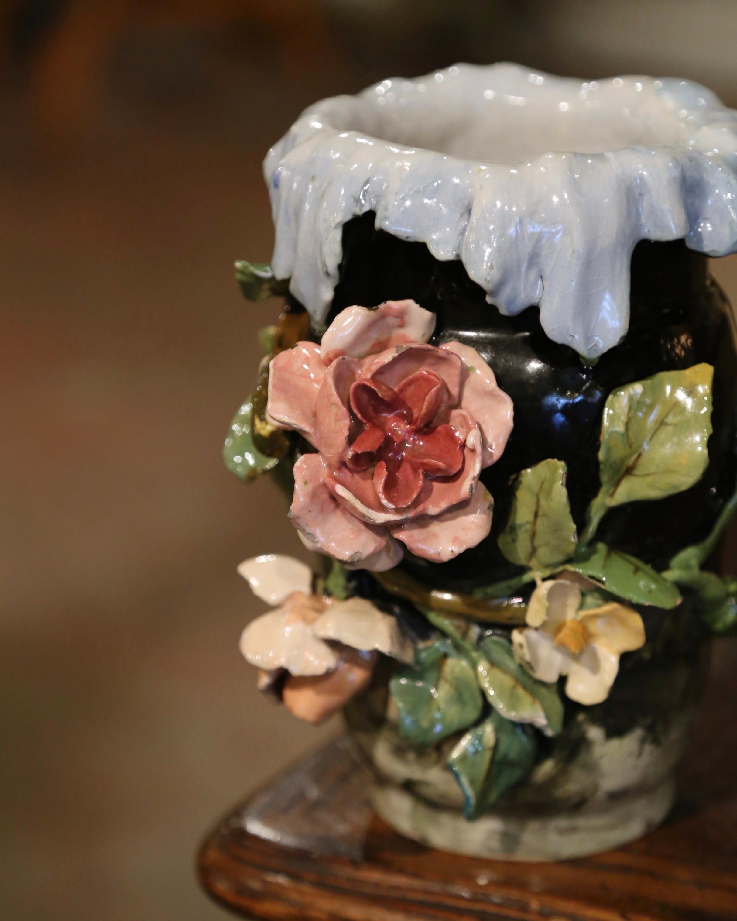 This colorful hand painted Majolica vase was sculpted in Montigny sur Loing, France, circa 1880. Round in shape with a scalloped rim and reverse leaves, the ceramic jardinière features floral and leaf decor in high relief on the front. The colorful