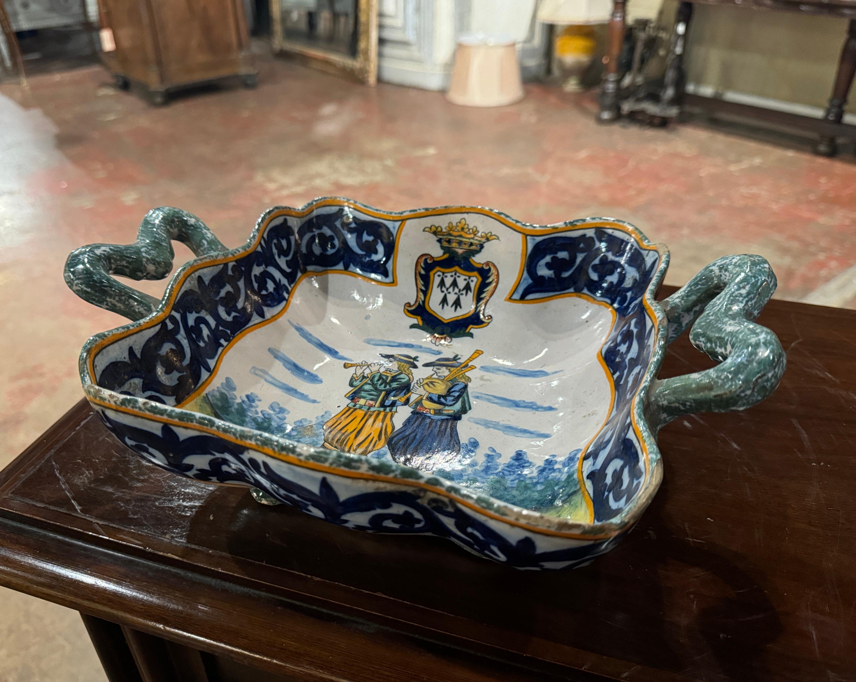 Serve chips or other appetizers in this elegant antique Quimper dish! Created in Brittany, France circa 1895 by Porquier Beau, the hand painted faience dish is square in shape, and dressed with scrolled handles. The serving platter is decorated at