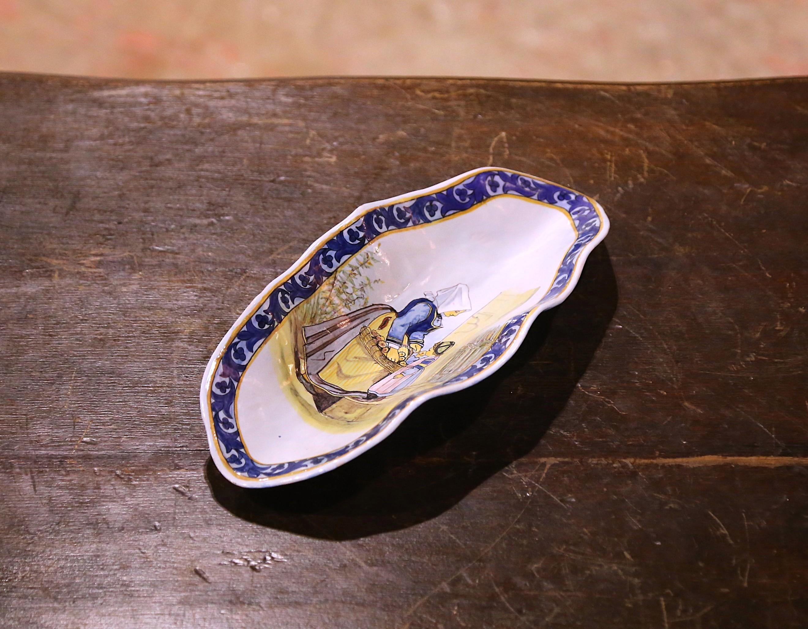 Servez des cacahuètes ou des olives dans cet élégant plat ancien. Créé en Bretagne vers 1890, ce plat en faïence peint à la main est de forme ovale avec des bords festonnés. Utilisé à l'origine pour servir des crêpes, le plat est décoré au centre