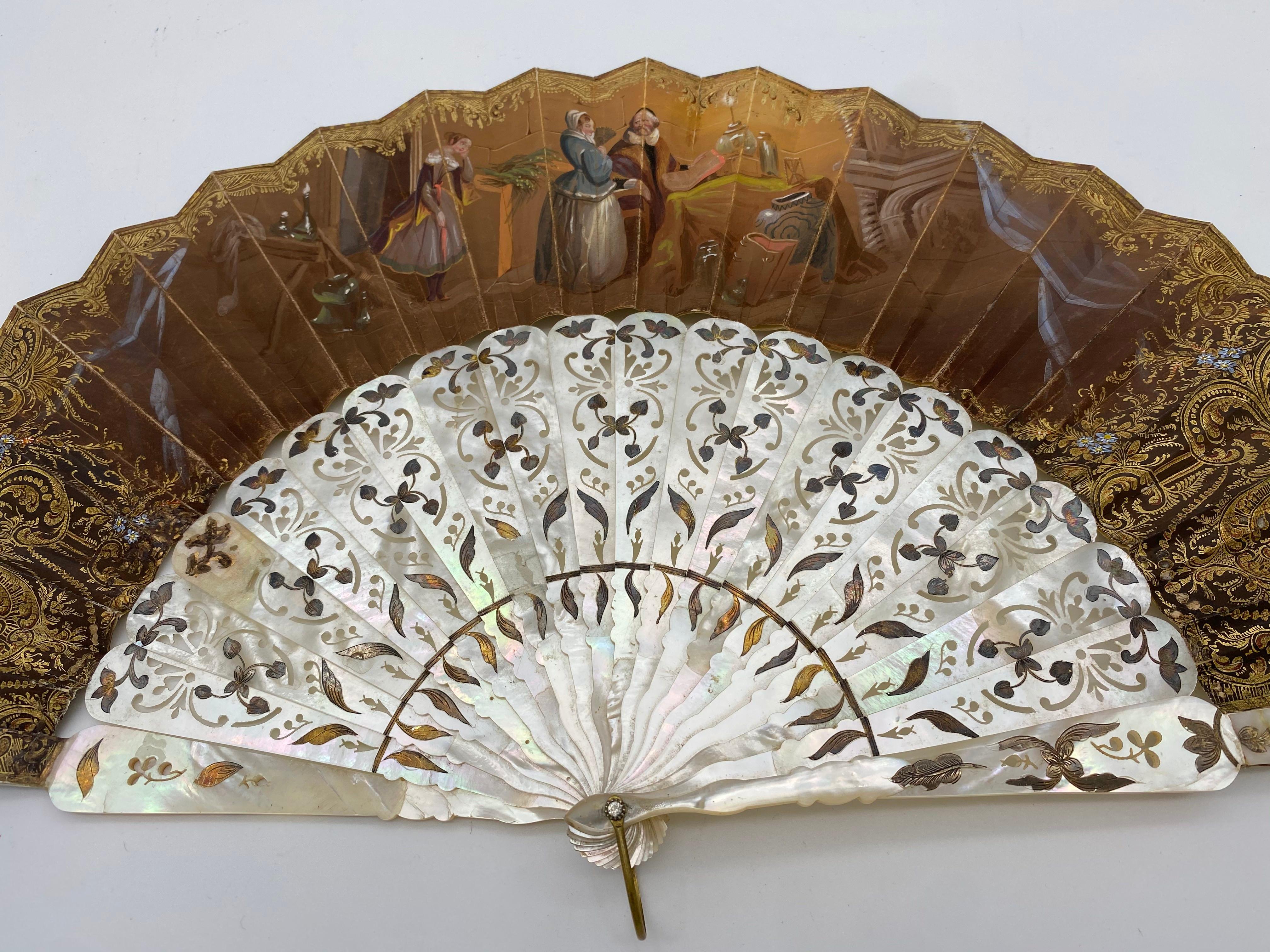 This ornate, antique paper and mother of pearl hand fan was crafted in France, circa 1850. the one side showing a candlelit interior where a young woman addresses a mage. Gallant scene on the reverse.