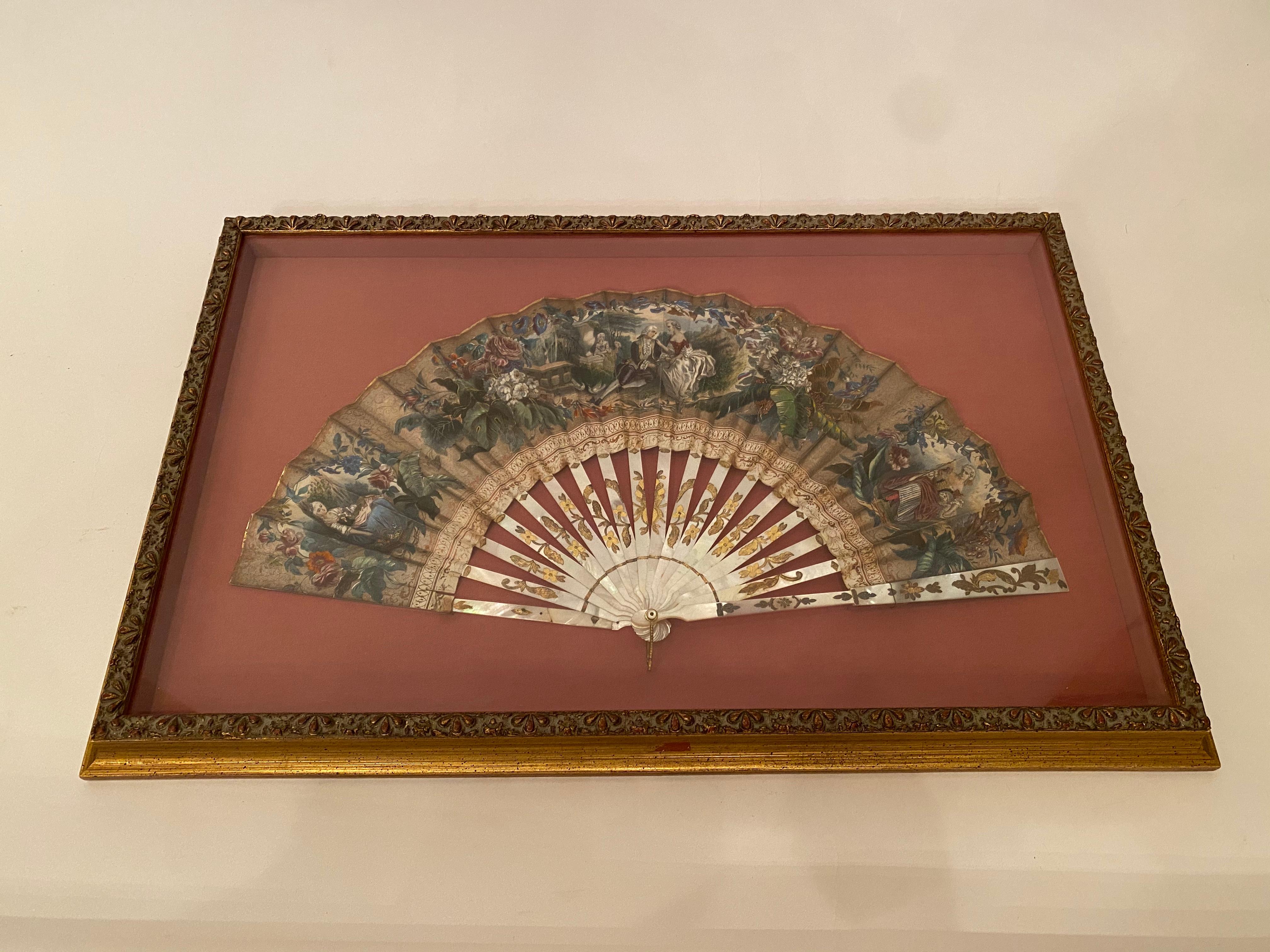19th century French painted paper and mother of pearl fan, shadow-box framed antique ladies fan, made of mother of pearl with a hand embellished regency-style lithograph, with gold leaf on the outer edge. The mother of pearl sticks have etched brass