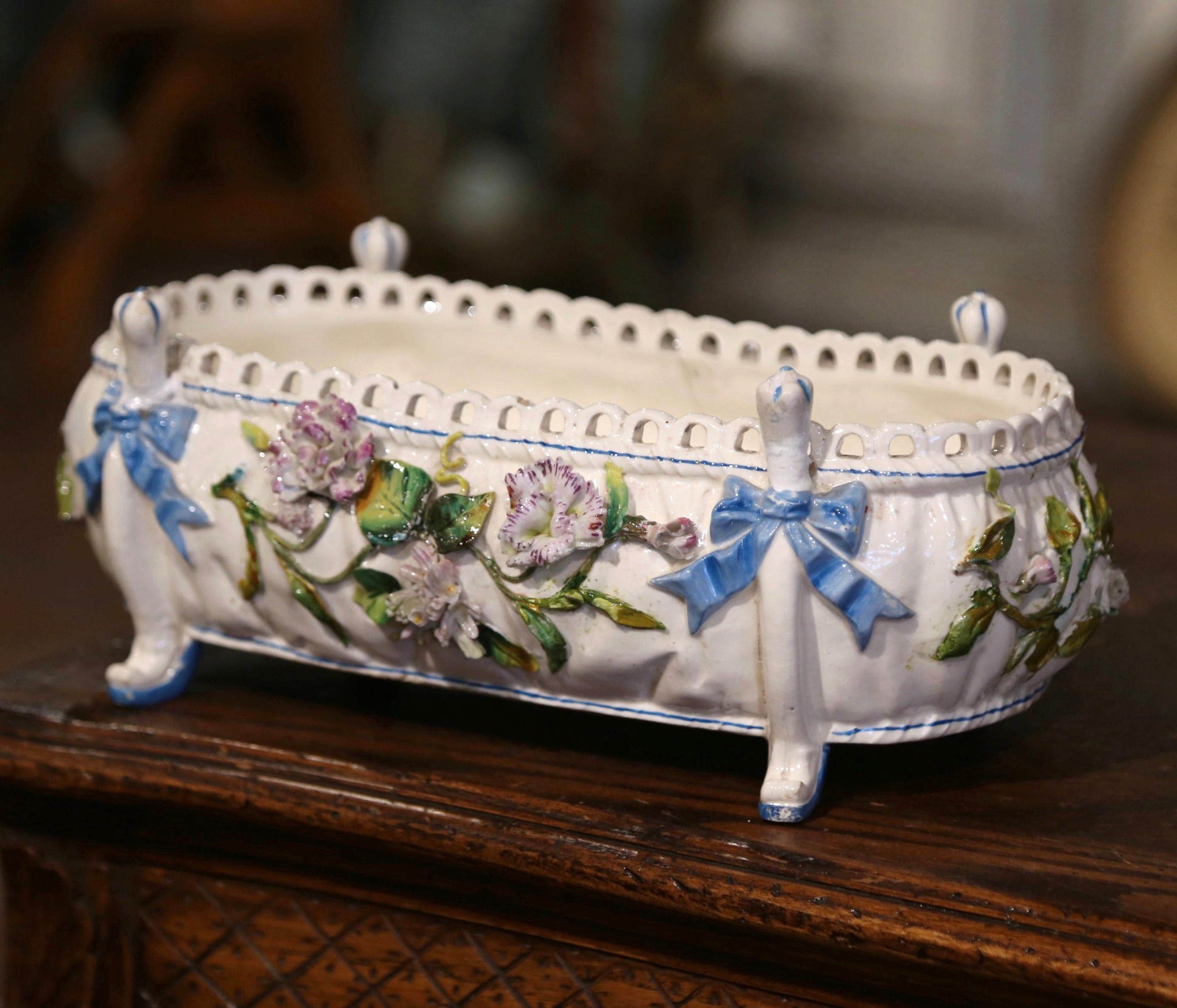 This beautiful and colorful Majolica cache pot was crafted in France, circa 1880. A Classic example of French barbotine artistry, the sculptural porcelain piece is oval in shape with bombe sides. Standing on scroll feet decorated with a ribbon bow