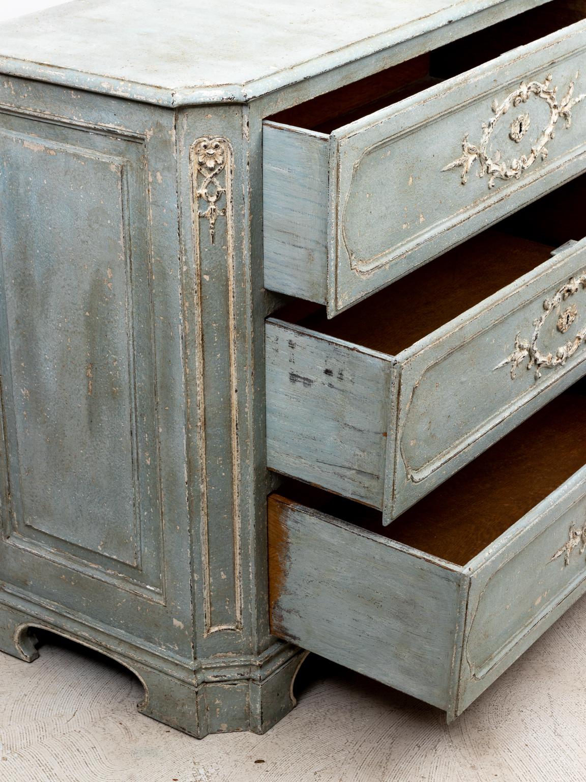 Circa 19th century French painted three drawer commode in the Rococo style ornamented with scrolled foliage and bellflowers on the drawer fronts. Please note of wear consistent with age including paint loss. Key included.