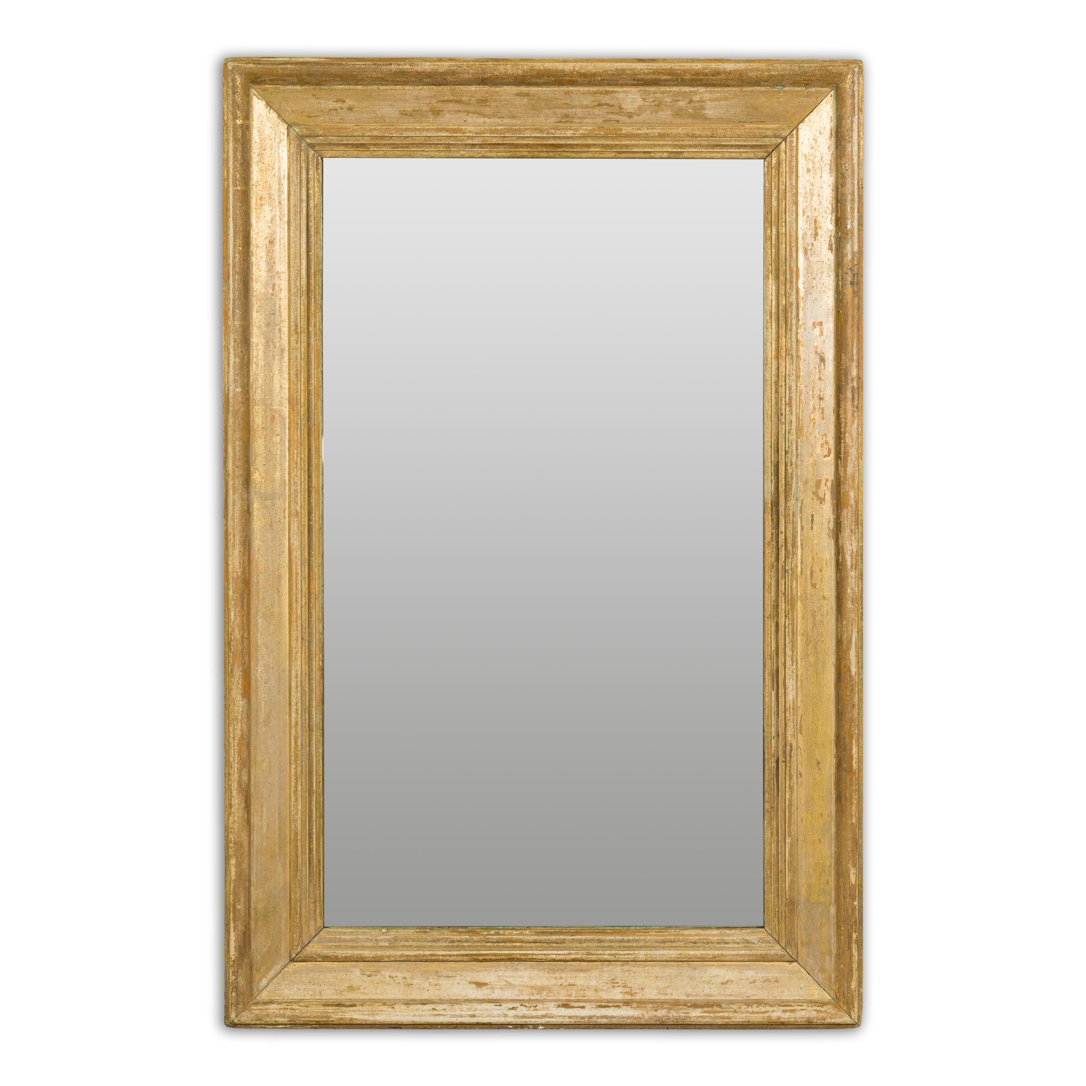 A French rectangular mirror from the 19th century painted with distressed golden tones and with molded accents. Embodying the refined elegance of 19th-century French design, this rectangular mirror is a testament to timeless sophistication. Crafted