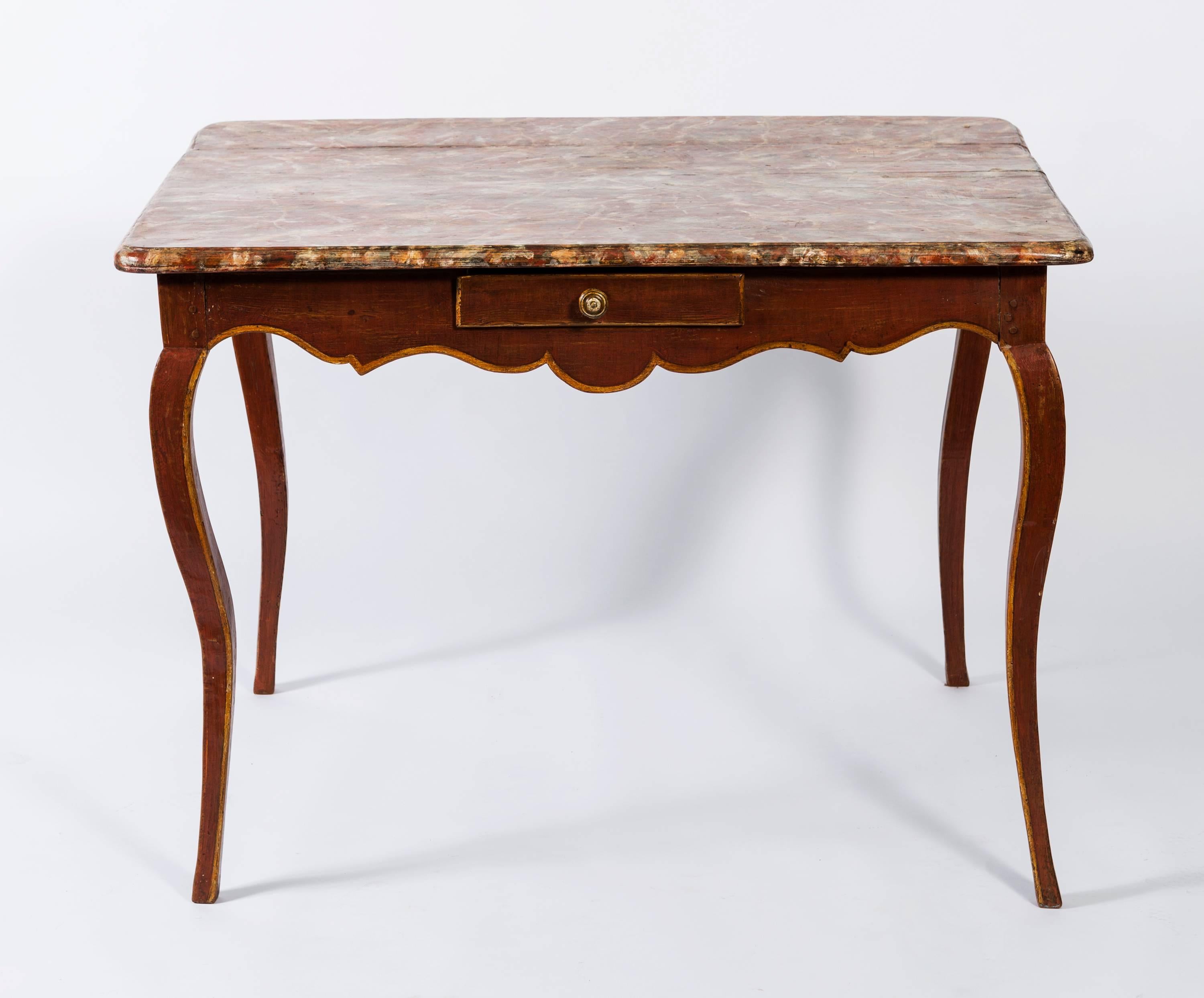 Beautiful 19th century terracotta painted wood rectangular table with faux marble top in complementary colors with a beveled edge. The center table is finished on all four sides and has cabriole legs. The apron is in a scroll pattern outlined on the