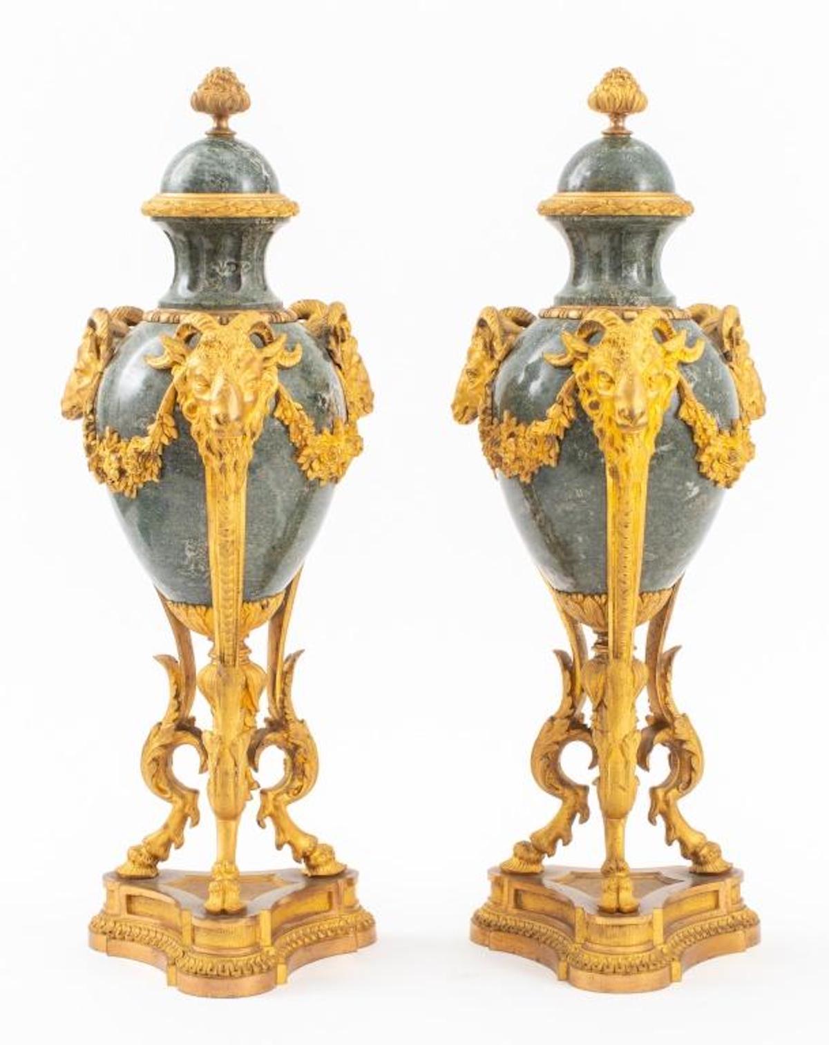 Large pair of baluster form gilt bronze-mounted marble decorative garnitures / urns, in the manner of Pierre Gouthiere (French, 1732-1813). Each footed urn / garniture features a fruiting finials above verde antico marble caps, fluted necks with