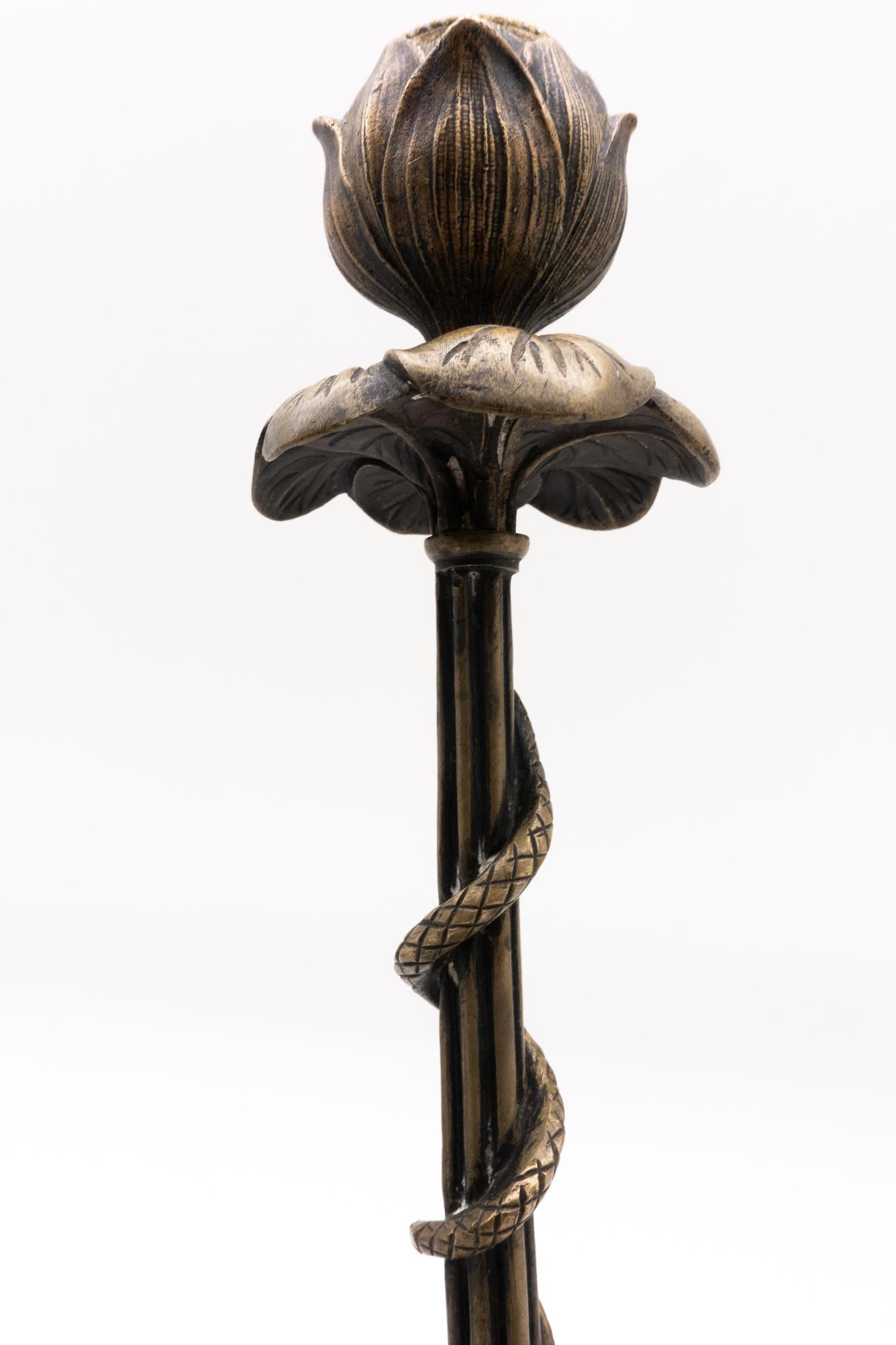 Beautiful pair of bronze Victor Paillard style French 19th century candlesticks resembling flower buds, each with a snake climbing down a reeded stem supported by a tripod base consisting of lion paws and leaves.