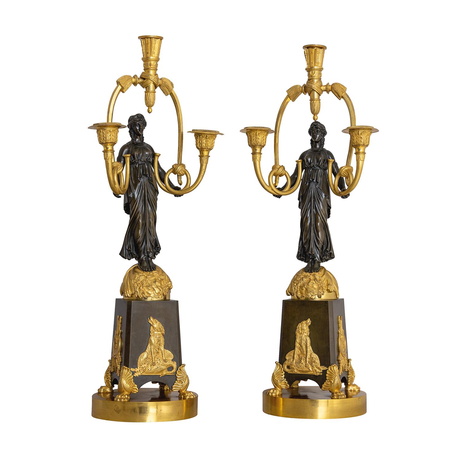 A gold-black, antique French pair of girandoles made of handcrafted gilded bronze attributed to Friedrich Bergenfeldt, in good condition. Each of the detailed Parisian candle holders are composed with a female warrior, particularized with hunting