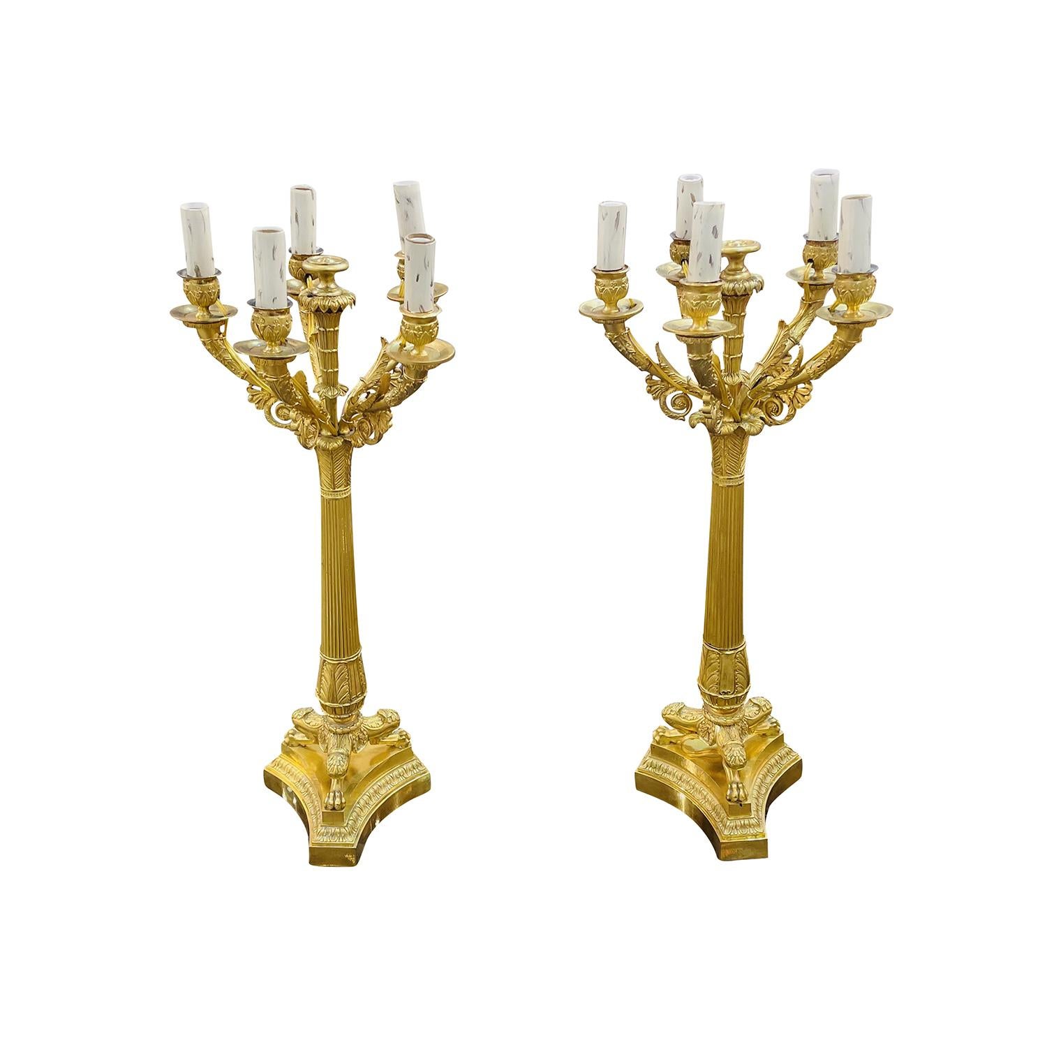 An antique pair of French Charles X candle holders, lights made of hand crafted gilded bronze, in good condition. Each of the detailed candelabras are composed with five candle sticks which are halted by short curved arms, supported by a tapering