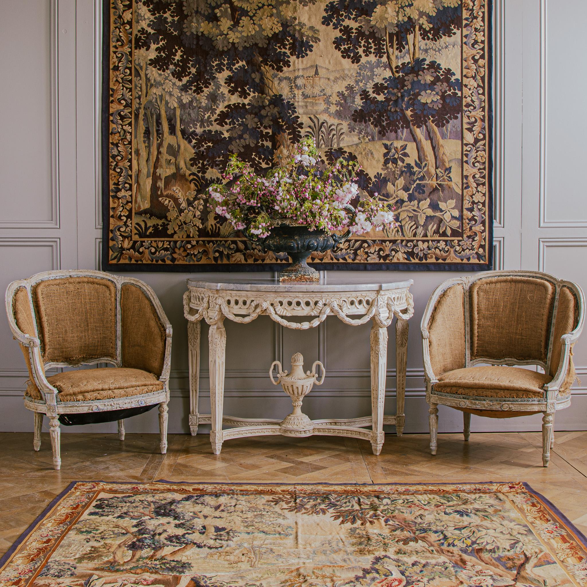 A rare find of exquisitely hand-carved  19th Century Corbeille Bergere, Louis XVI Style, French Armchairs, Circa 1800s. The Chairs have beautiful proportions with the attention to detailing of the period. The patina has a naturally age-distressed