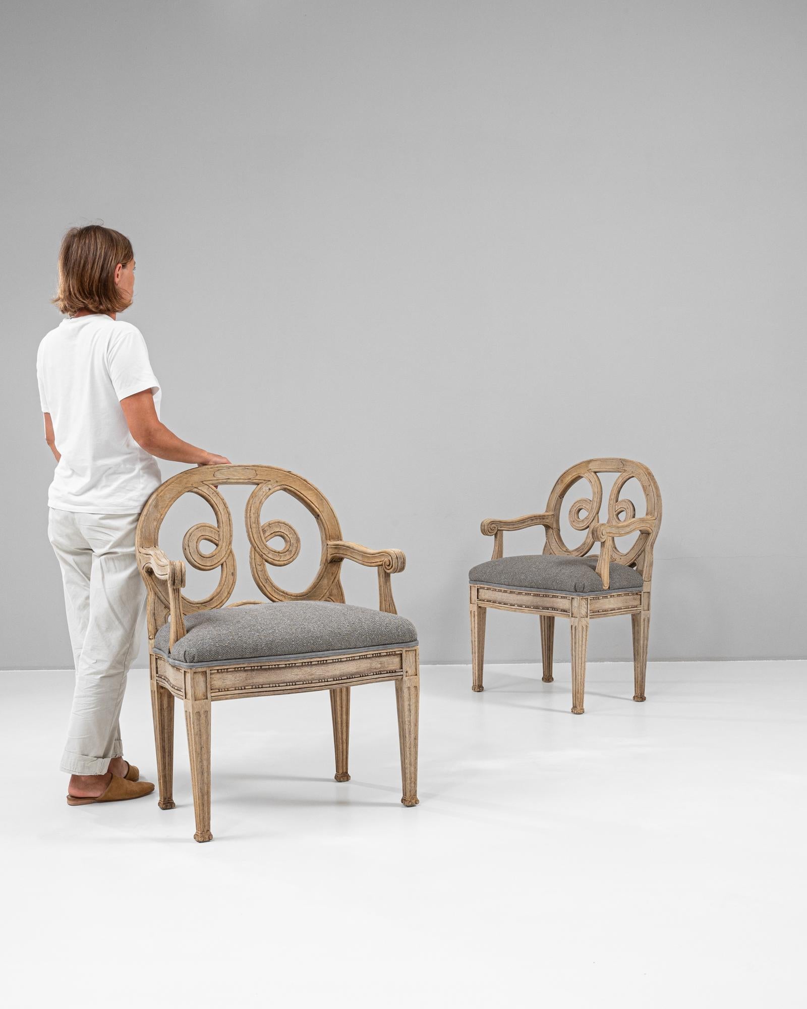 Esta pareja de sillones franceses de roble del siglo XIX desprende una elegancia atemporal con un intrincado trabajo artesanal. Los elegantes diseños arremolinados de los respaldos abiertos crean un punto focal, mientras que el marco de roble