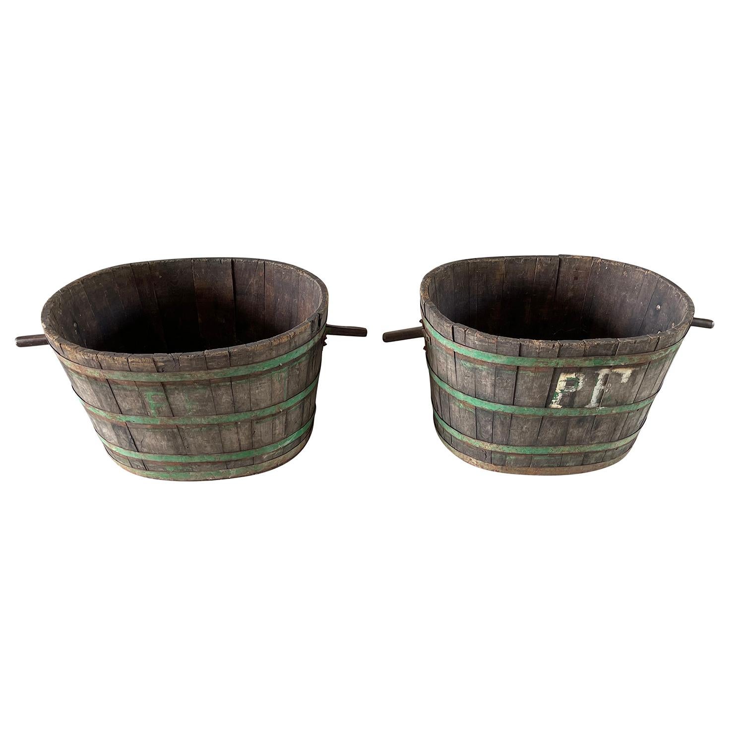 A pair of charming antique Oakwood large buckets or troughs with iron handles and green patinated iron bands, in good condition. These oval bins from Burgundy were typically used to collect grapes. The iron handles of the vessels were used to be