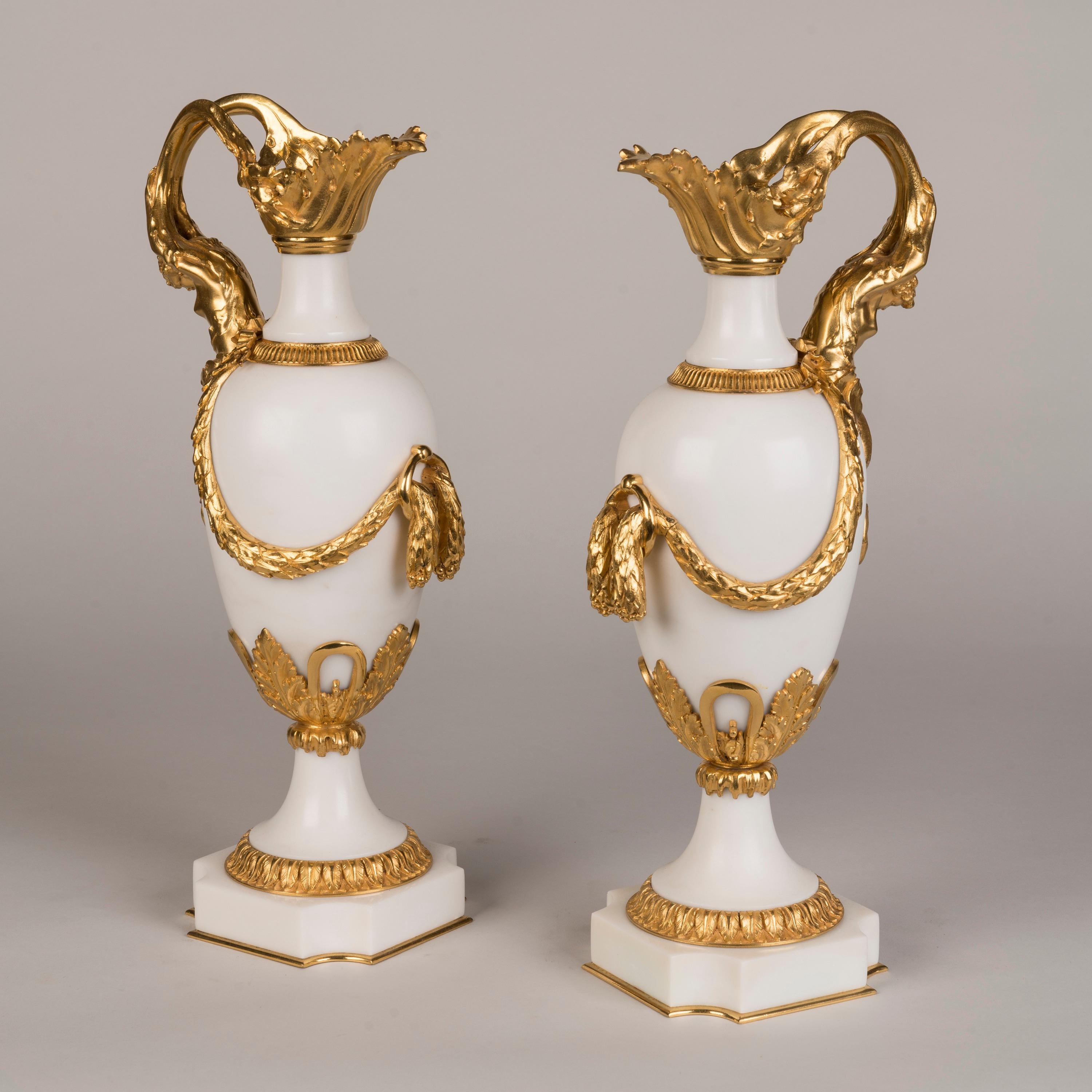 Ein Paar Ormolu-gefasste Marmorvasen
Im Stil von Louis XVI

Eiförmige Vasen aus reinem Carrara-Marmor, auf gewölbten Sockeln und taillierten Sockeln mit steifen Blattbordüren, aufwändig mit Ormolu beschlagen, mit geformter Tülle, die einen Henkel