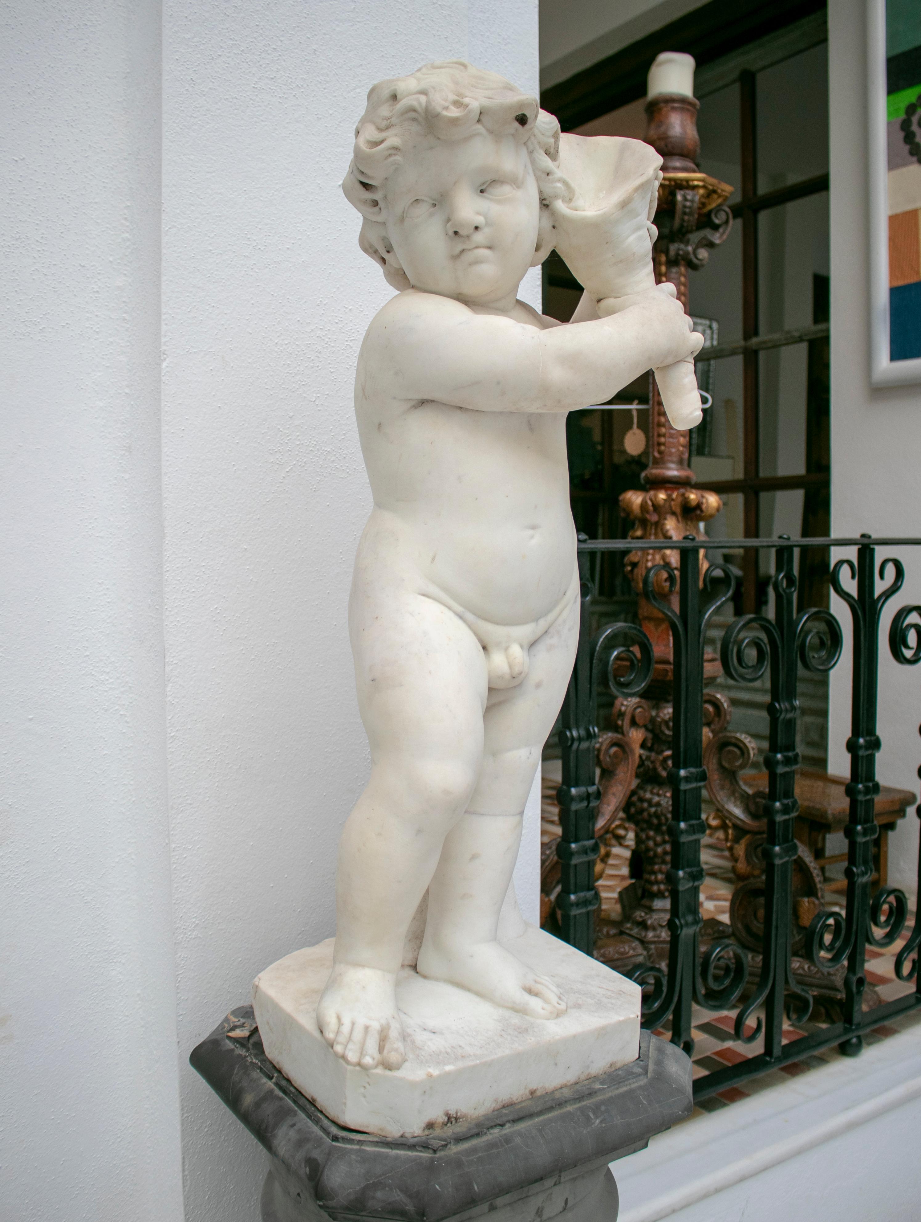 19th century French pair of white Carrara marble child sculptures, one holding a cornucopia or horn of plenty and the other a sea conch.

 