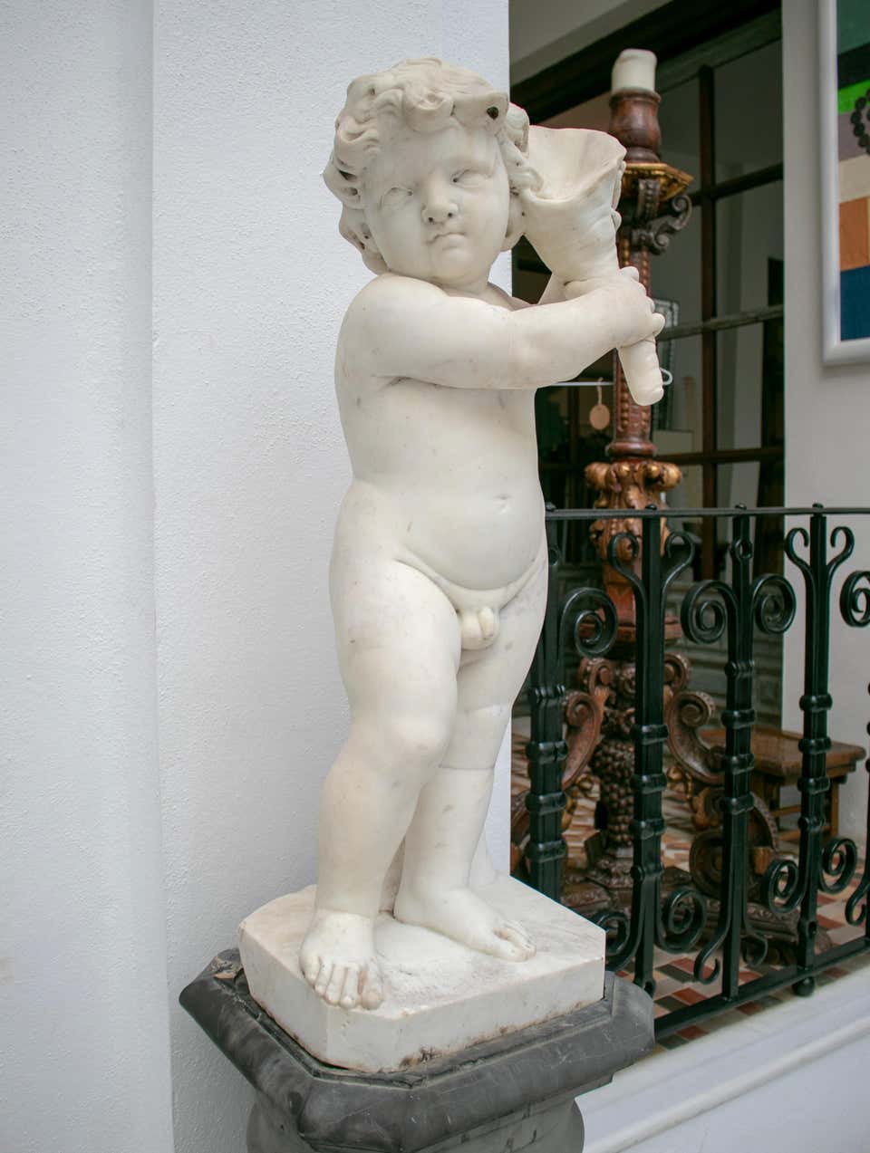 19th century French pair of white Carrara marble child sculptures, one holding a cornucopia or horn of plenty and the other a sea conch.
