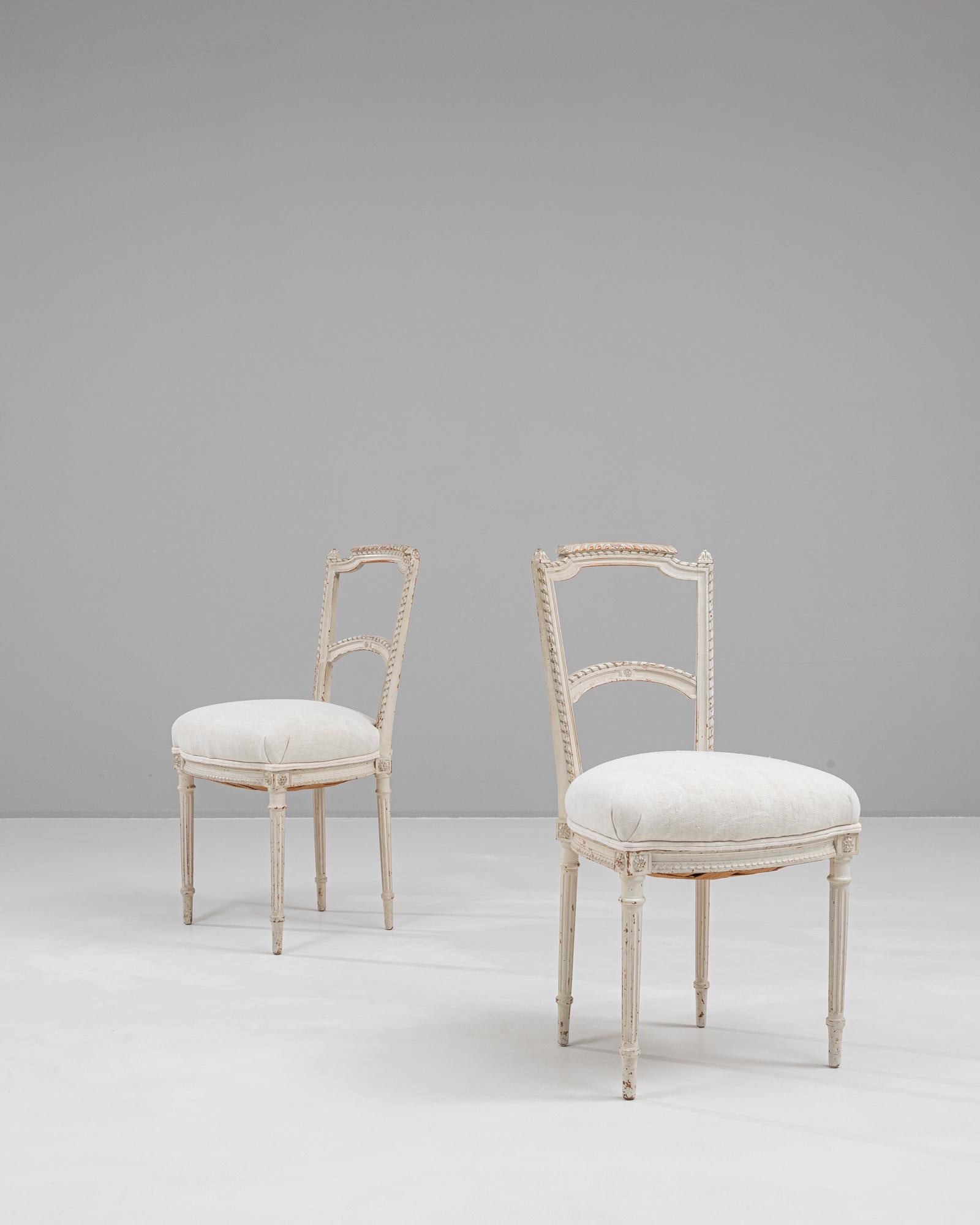 Dieses elegante Paar französischer Esszimmerstühle aus dem 19. Jahrhundert strahlt klassische Raffinesse aus. Die sorgfältig aus Holz gefertigten Rahmen haben eine weiß patinierte Oberfläche, die ihren zeitlosen Reiz unterstreicht. Zarte,