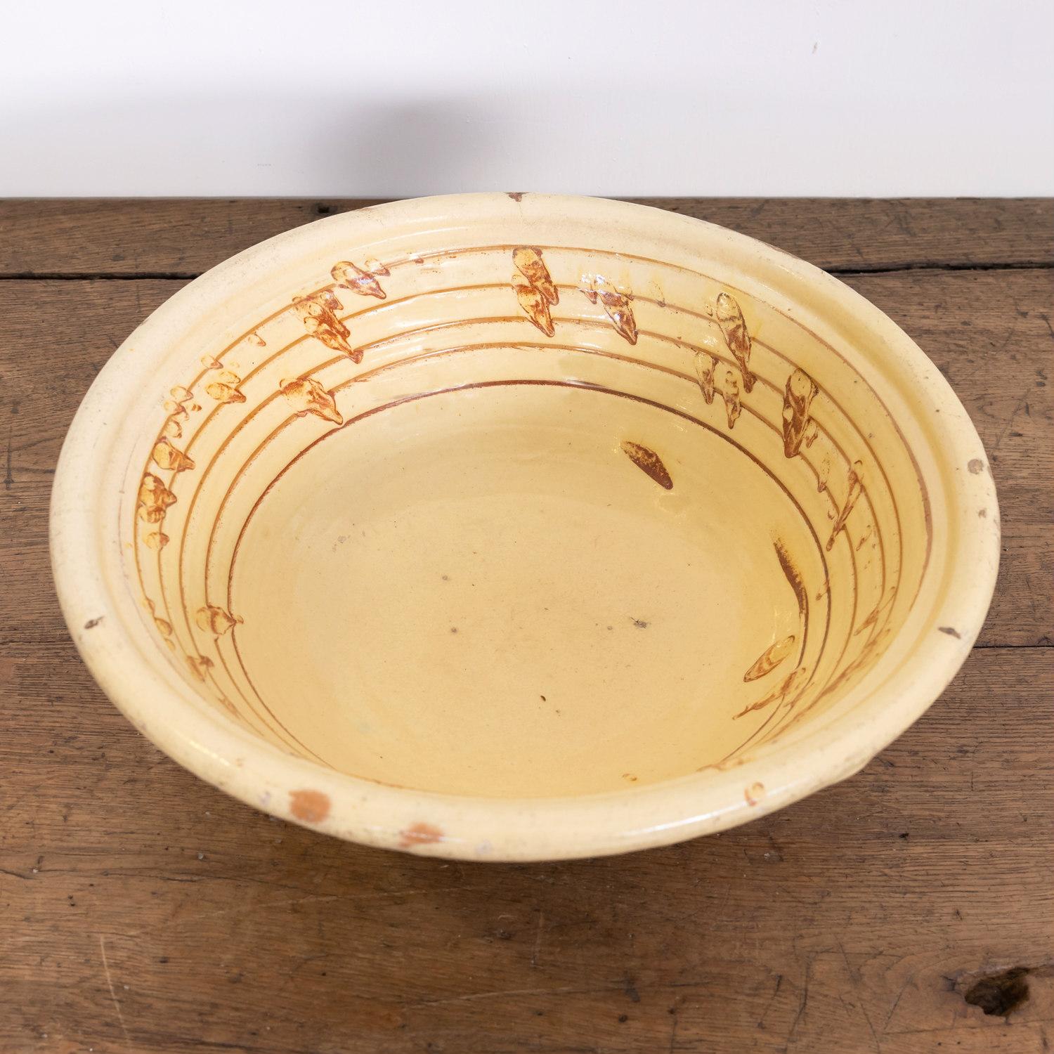 A late 19th century French pancheon or dough bowl with an interior honey yellow glaze and caramel splatters, circa 1880s. Pancheons were multipurpose terracotta kitchen bowls used during the 17th, 18th, and 19th centuries. In addition to being used