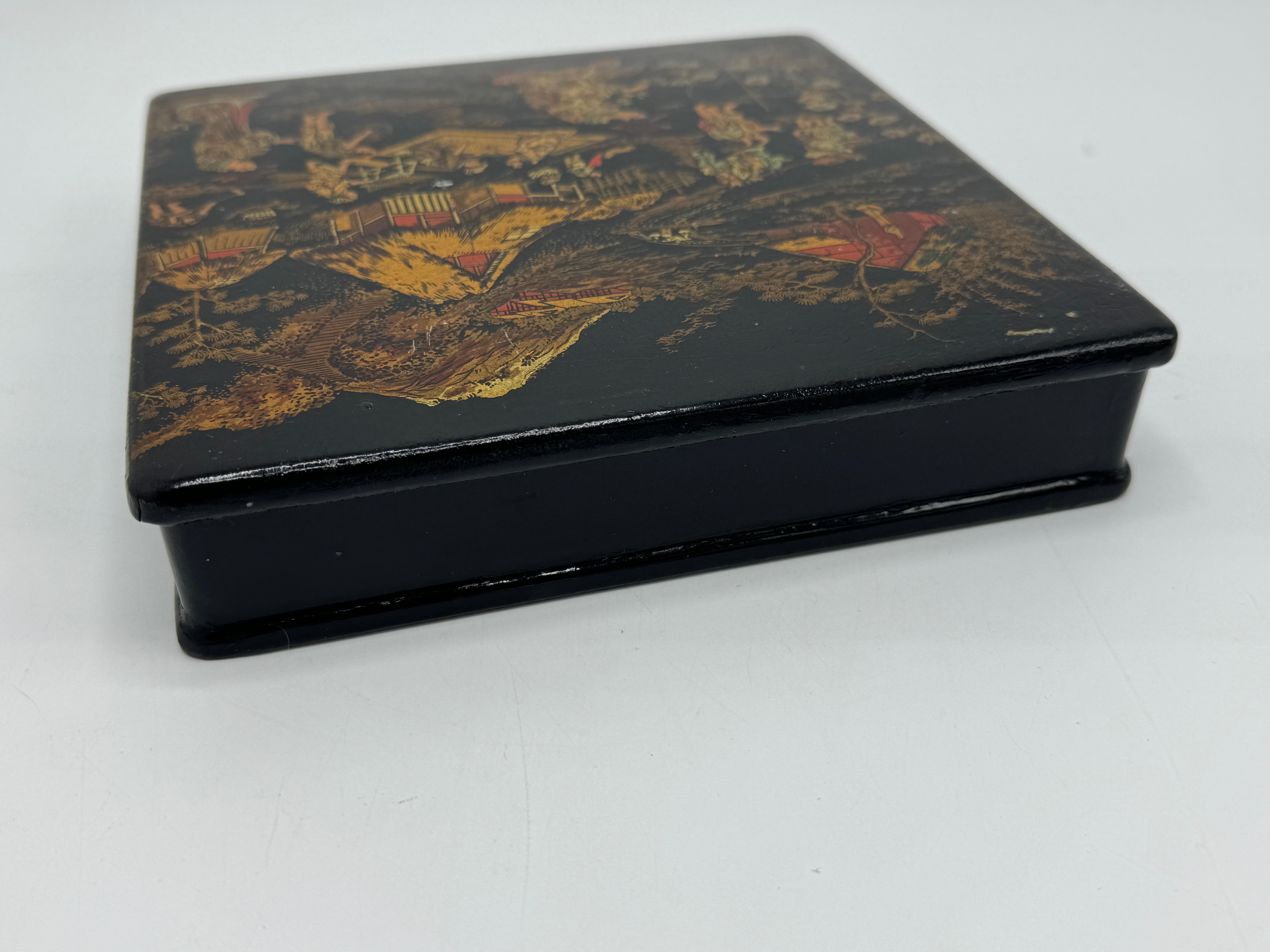 Offered is an excellent example of 19th century French papier mâché in the form of a square box, decorated with gold and red Chinoiserie scenes on black lacquer. While Eastern in design, the Chinoiserie craze swept France in the 1800's, leading to