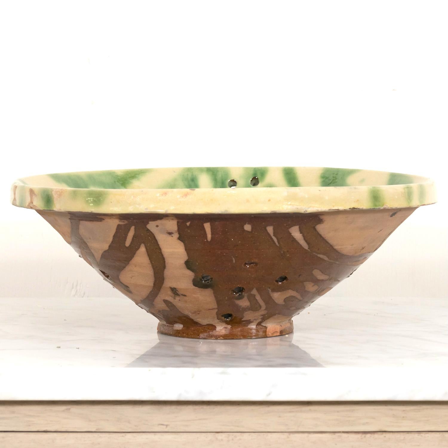 A lovely 19th century French passoire en terre cuite or colander, circa 1890s, handmade of terracotta in Perpignan, known as the capital of French Catalonia, near the foothills of the Pyrénées. This charming utilitarian bowl, used for washing and