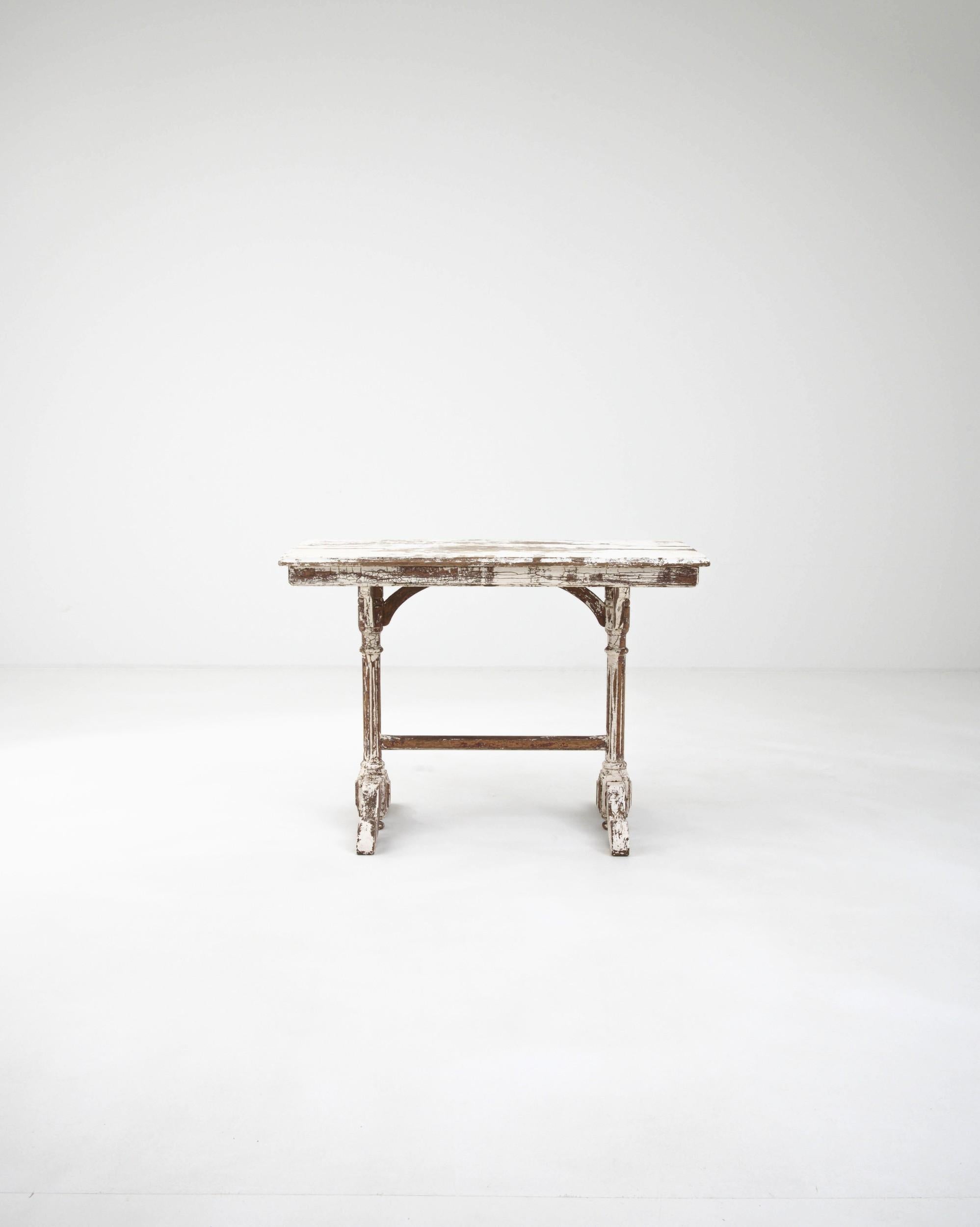 Elegant and nostalgic, this antique wooden side table evokes the nostalgia of a bygone age. Built in France in the 1800s, a rectangular tabletop sits atop a light and graceful trestle base. The slender columns of the legs are counterbalanced by the
