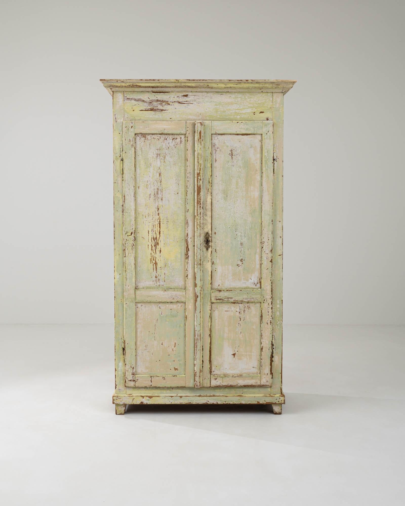 Crafted during the 19th century in France, this antique wooden cabinet showcases a distinctive patina gradient, transitioning from light green to yellow-white, with a subtly distressed finish that reveals the soft tawny wood underneath. The