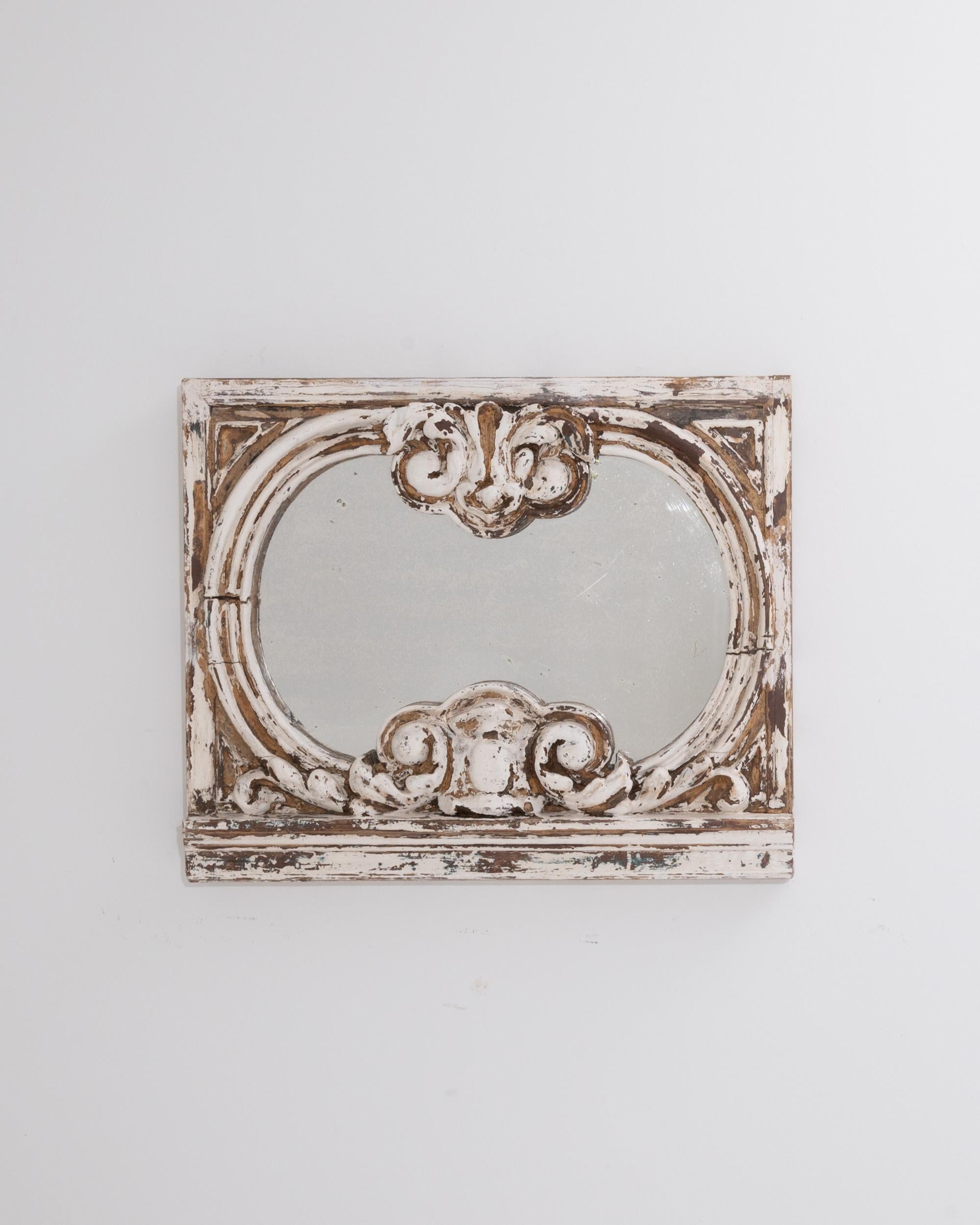 A timeworn patina gives this antique wooden mirror an eye-catching personality. Made in France in the 1800s, the pronounced forms and deep relief of the carved wooden frame create an impression of Baroque grandeur. Bold curves parenthesize the