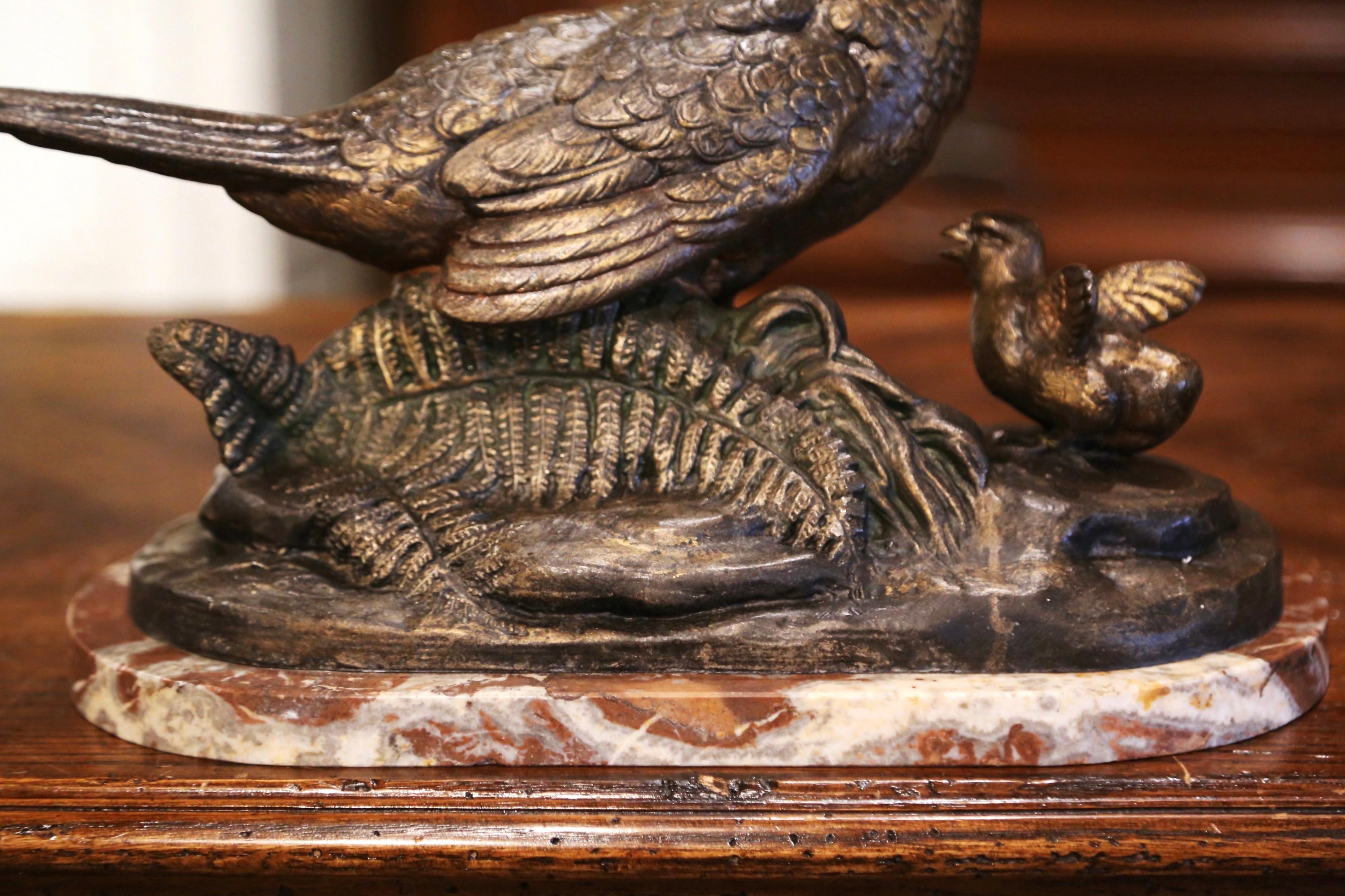 Decorate a man's office or desk with this elegant antique bird sculpture. Crafted in France circa 1890 and standing on a variegated marble base, the sculpture depicts a female pheasant watching over her baby pheasling. The spelter figure is signed