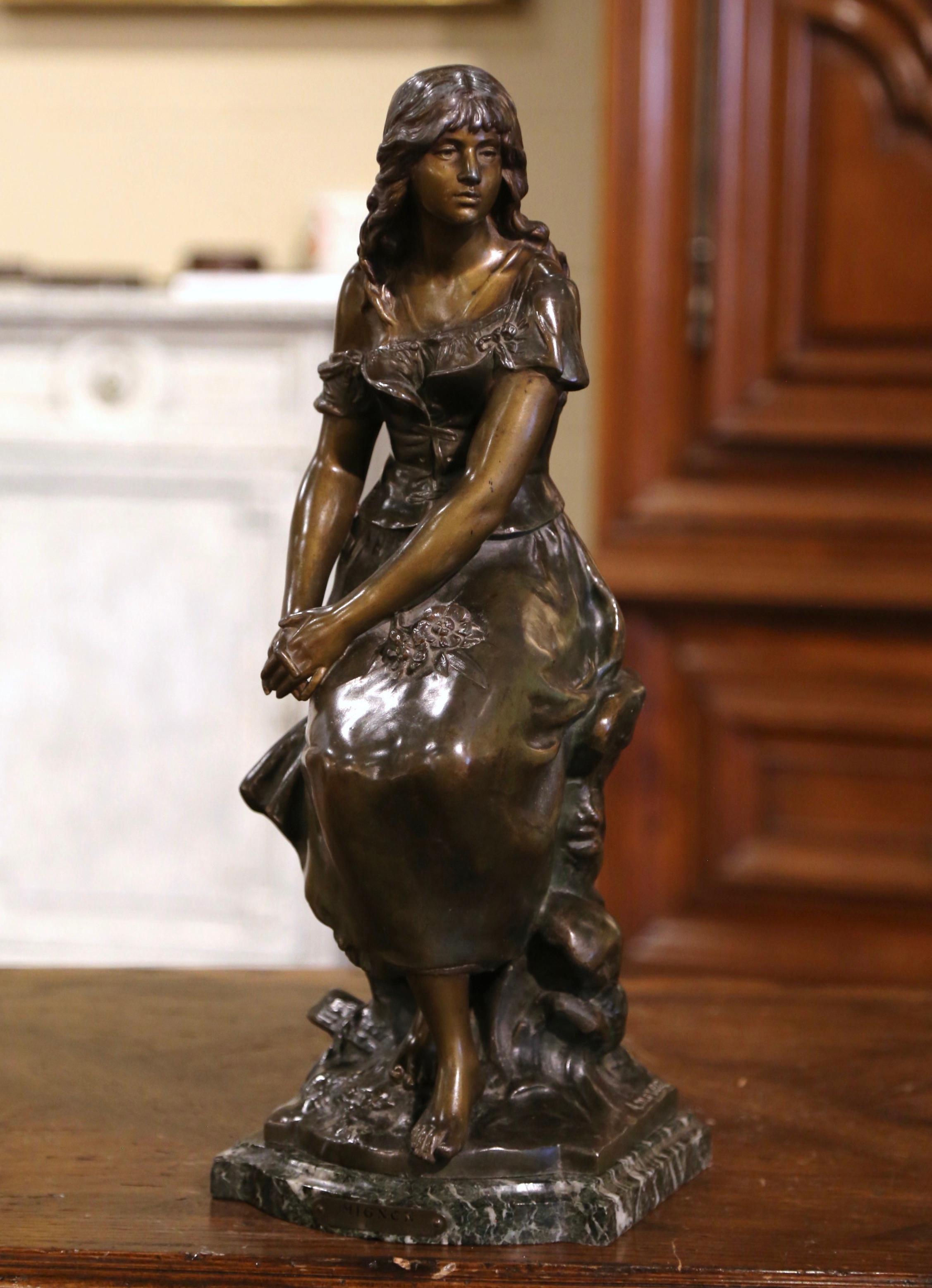 This elegant figure composition was crafted in France circa 1880. Built of spelter, the statue stands on a shaped black and grey marble base, and depicts a young female beauty seated on a trunk, her hands crossed on her thighs. The tall composition