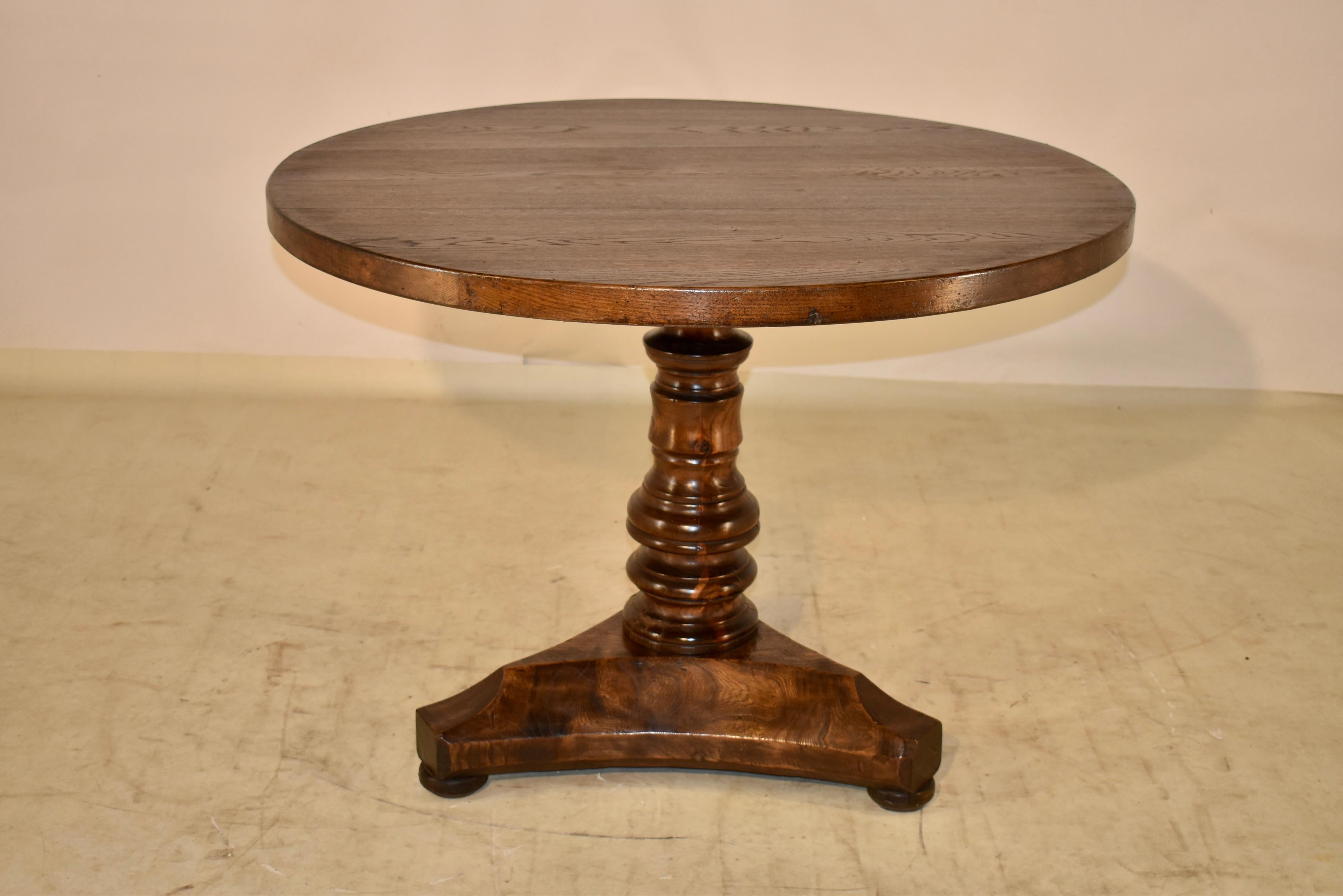 19th century oak and elm table from France. The top is 1.75 inches thick and is made from oak planks. It is supported on a hand turned pedestal. The pedestal and tripod shaped base are hand carved from elm and has wonderful graining and color. The