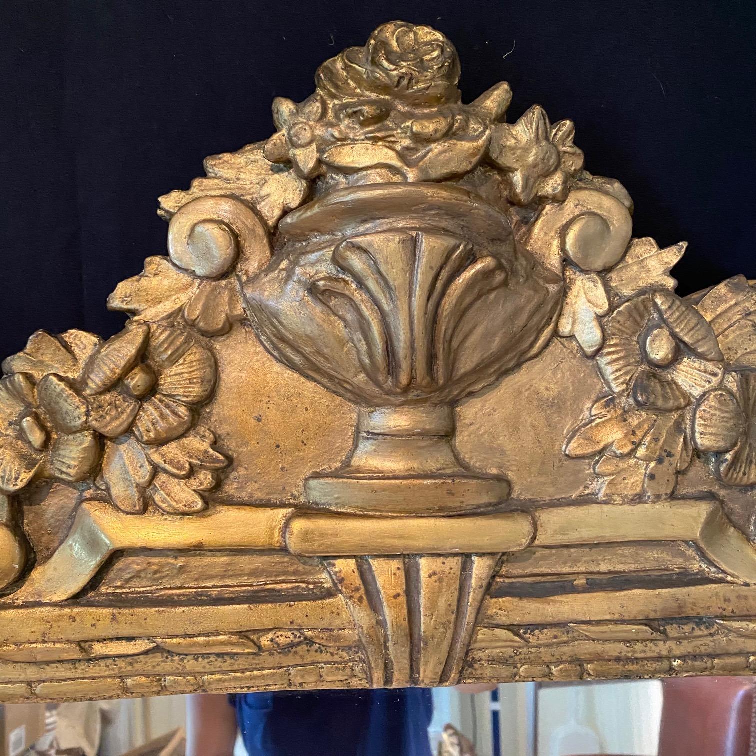 Miroir de France d'époque Louis XVI. Cette pièce est en bois stuqué et sculpté à la main, avec un fronton représentant une urne et de jolis motifs floraux.

#6462