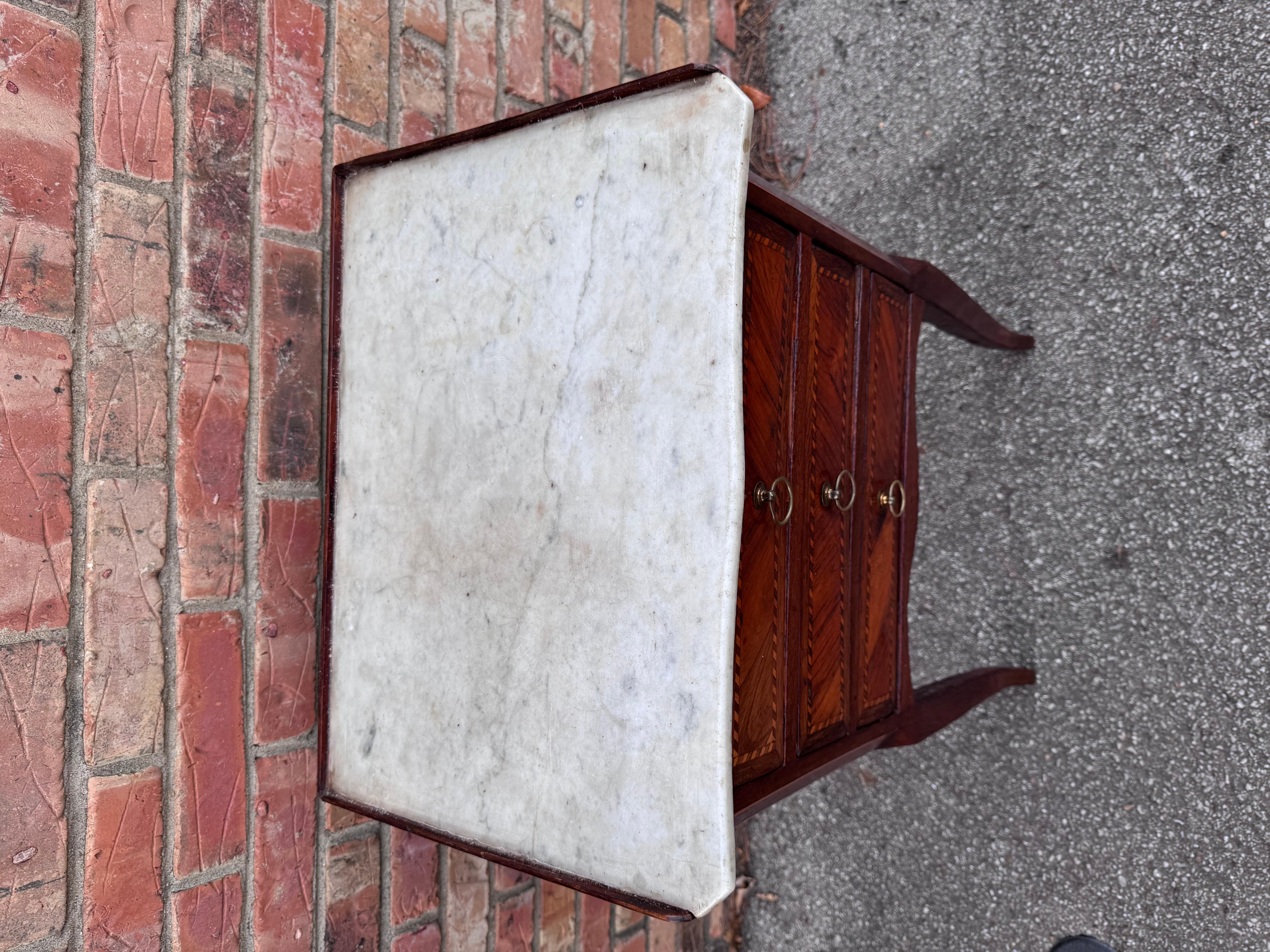 This beautiful French side table features a marble top and gorgeous inlay and burl veneer on the face.
This could make a lovely addition in a bedroom, bathroom, living room or library. 

DIMENSIONS
18ʺW × 13.5ʺD × 29.5ʺH
