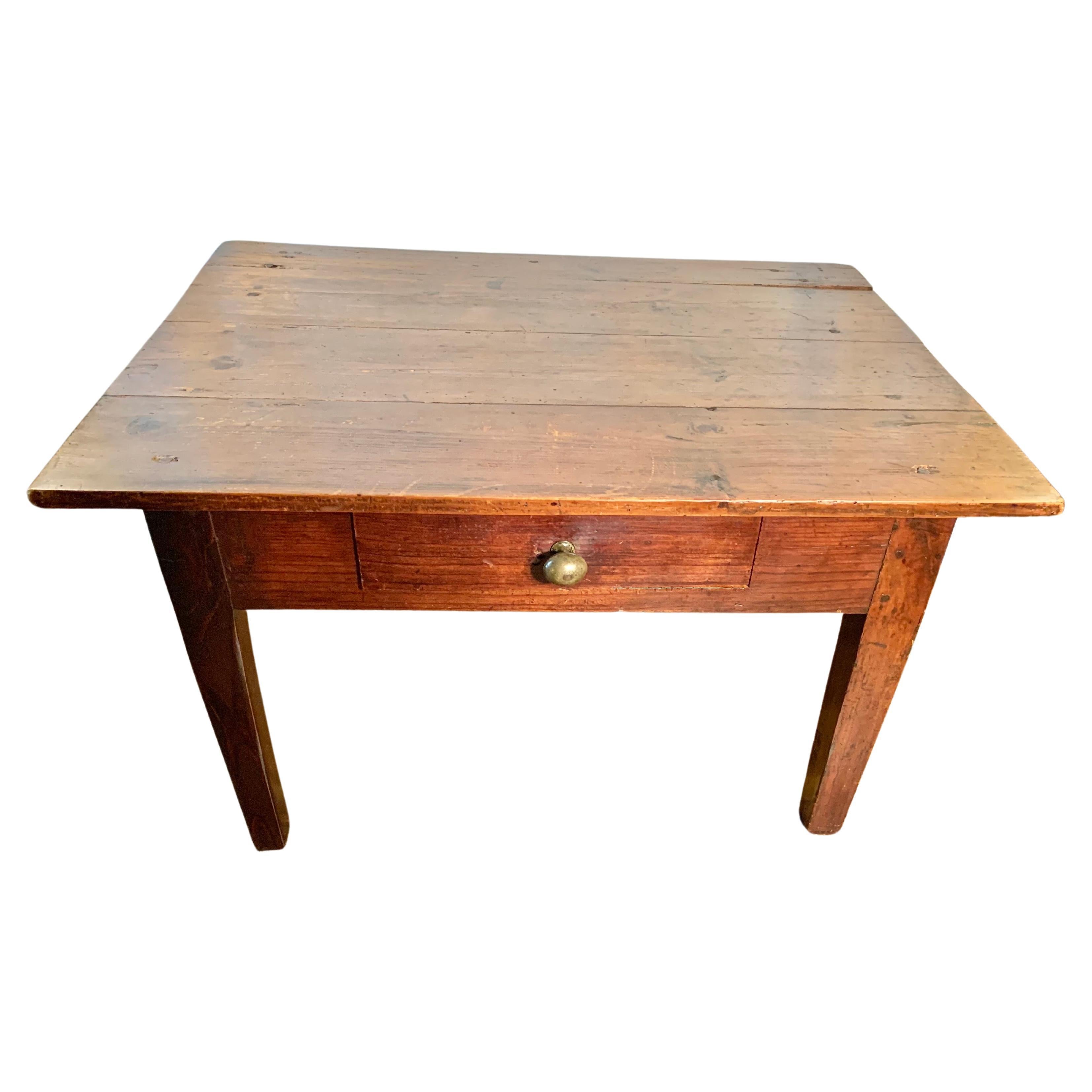 Trouvée dans le sud de la France, cette table basse du XIXe siècle a été fabriquée en pin ancien par des artisans français dans les années 1800. Cette pièce est chevillée à la main et présente un plateau à quatre planches reposant sur un tiroir et