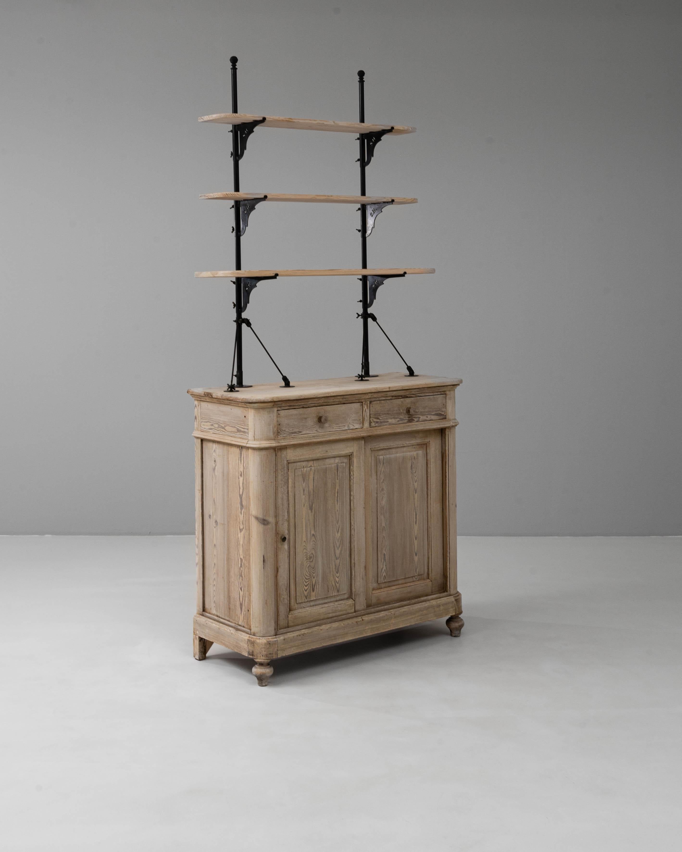 Questa vetrina francese del XIX secolo è realizzata in pino massiccio e presenta una splendida finitura naturale invecchiata che mette in risalto le venature e il carattere del legno. La base comprende due cassetti e ante a pannelli per riporre