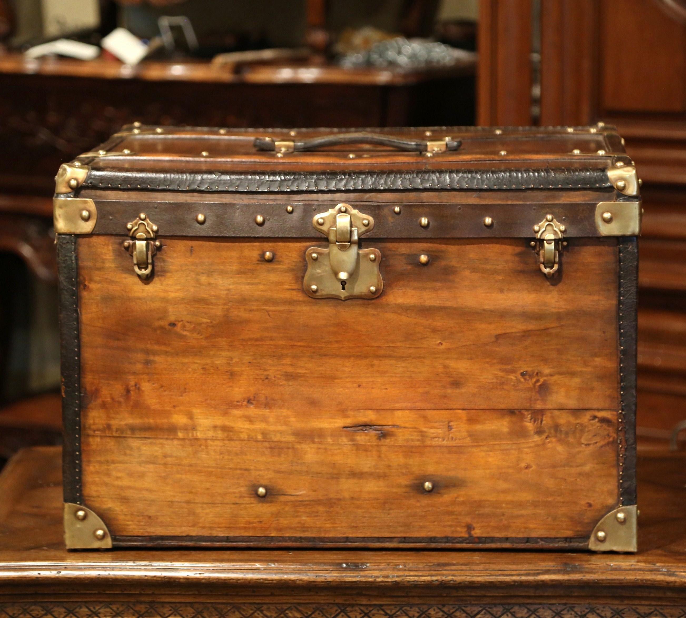Almost square in shape, this hat suitcase was crafted in Paris, France, circa 1890. The pine box with centre handle features decorative brass mounts in the corners and leather straps embellished with brass nailheads. The inside is upholstered with