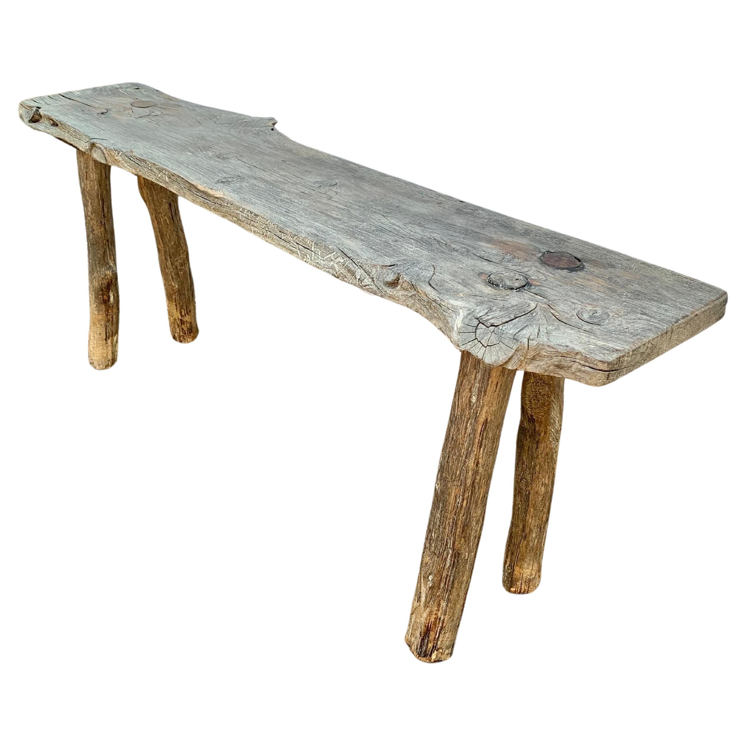 This charming 19th Century French bench was found in the South of France. Sturdily constructed from pine and having a great patina, the bench features four legs pegged into the live edge seat. This simply made sculptural wood bench is perfect for