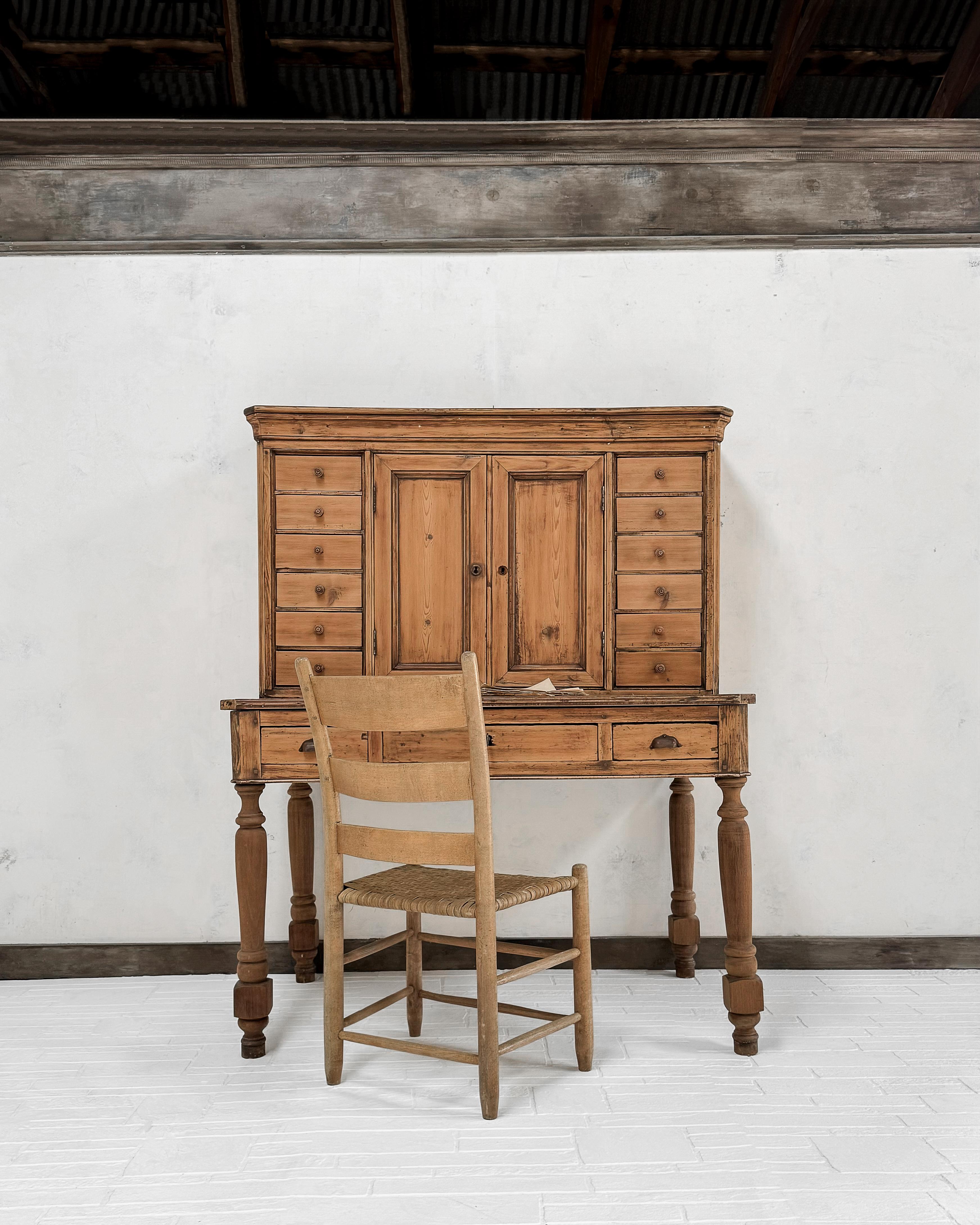 A unique writing desk found in France. Crafted from pine, the desk has been stripped to its natural wood finish (as found), and traces of the old stain remain. This wonderful piece boasts an abundance of storage options, featuring an array of 15