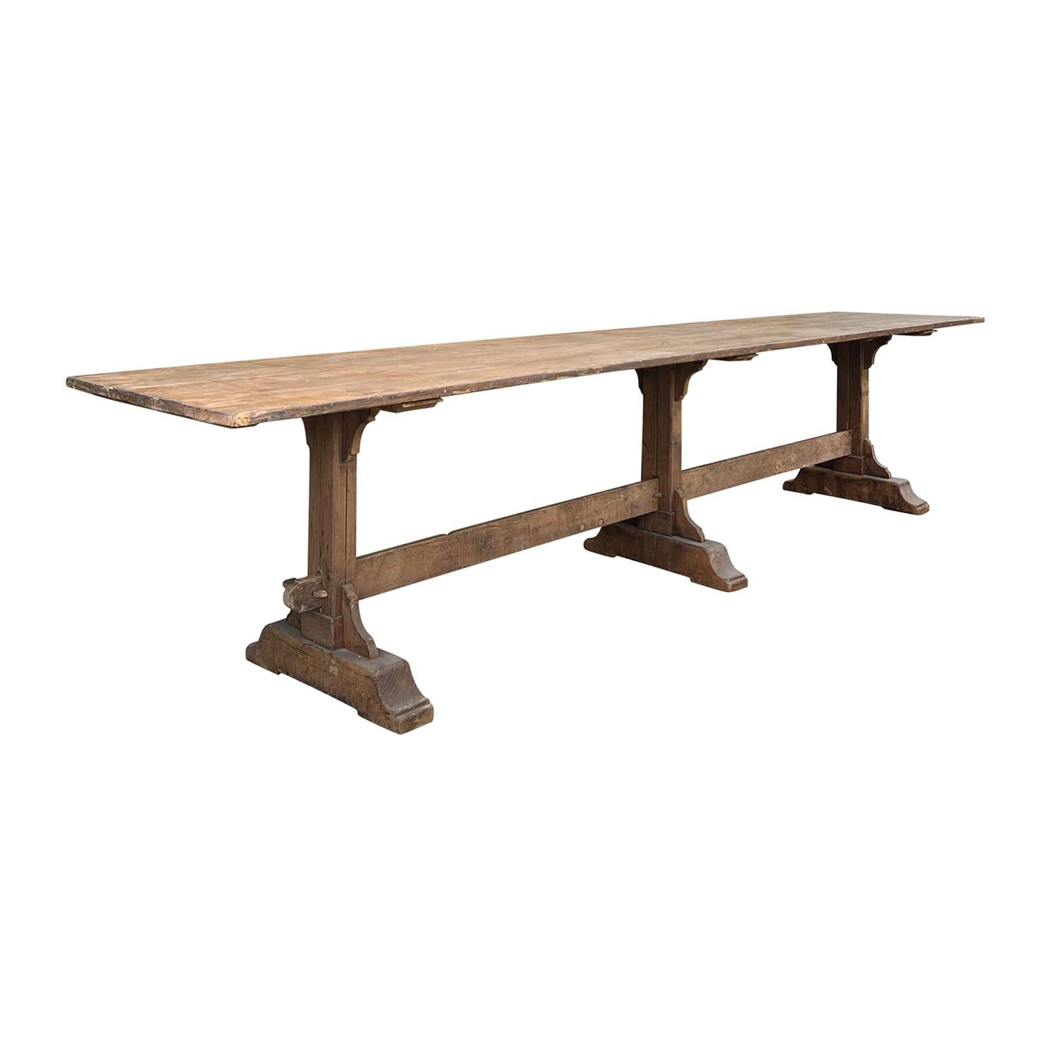 This antique oversized French solid Pinewood trestle base table is perfect for your casual dining experience, in good condition. The hand-crafted 11’ 11” long wooden table has a 1” thick top which is the perfect scale over the three sloping table