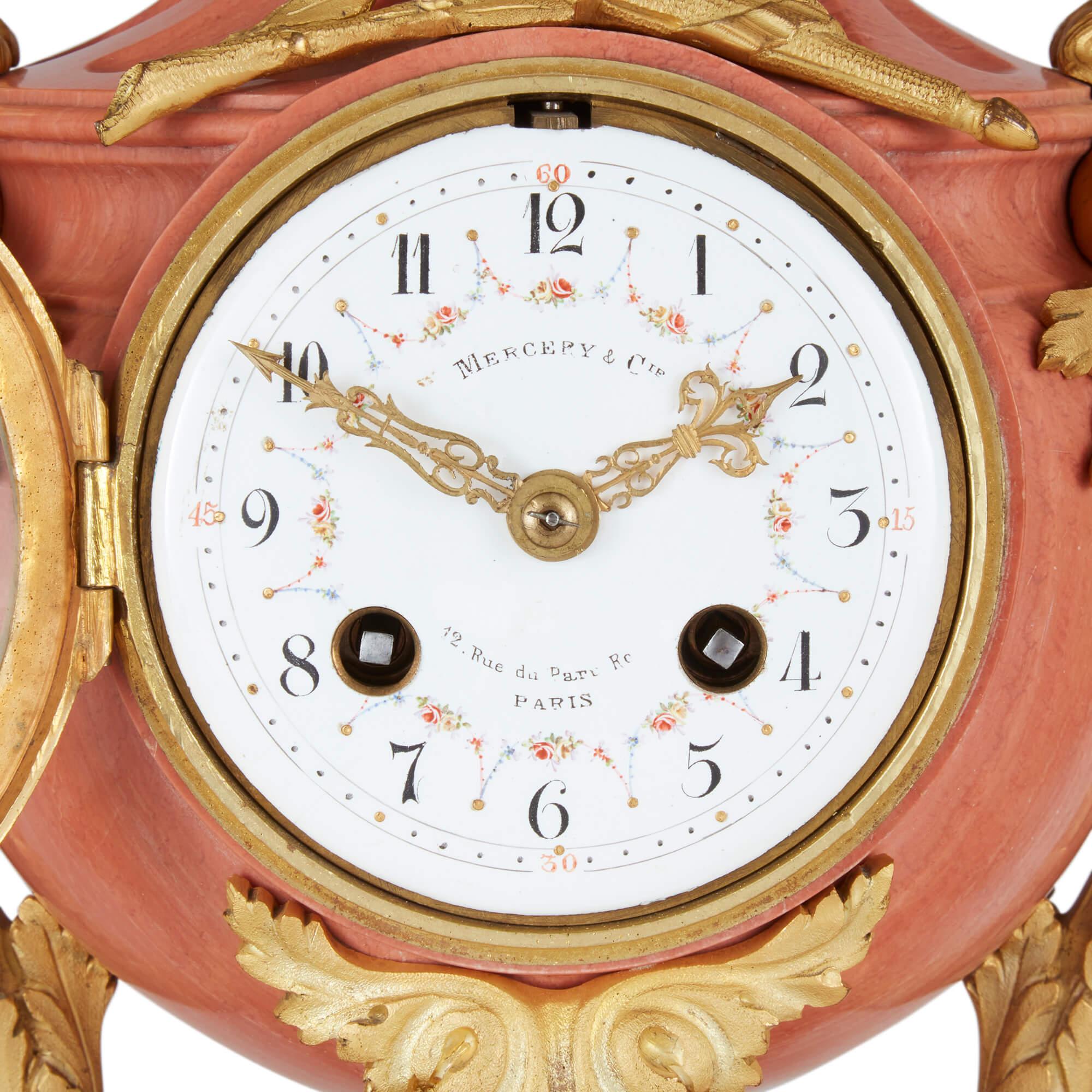 19th Century French pink marble and ormolu clock set 
French, Late 19th Century 
Clock: Height 46cm, width 23cm, depth 18cm 
Candelabra: Height 44.5cm, width 22cm, depth 20cm

This unusual three-piece clock garniture combines stunning pink marble