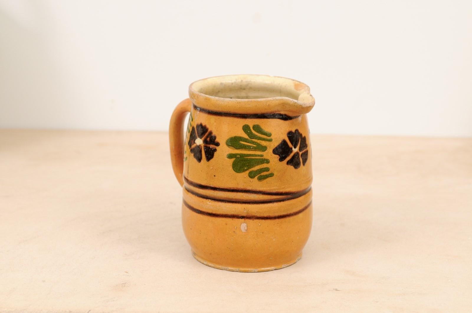 A French rustic pitcher from the 19th century, with yellow, brown and green glaze. Created in France during the 19th century, this charming pitcher features a yellow glazed ground adorned with brown pansies and their green leaves, separated from the