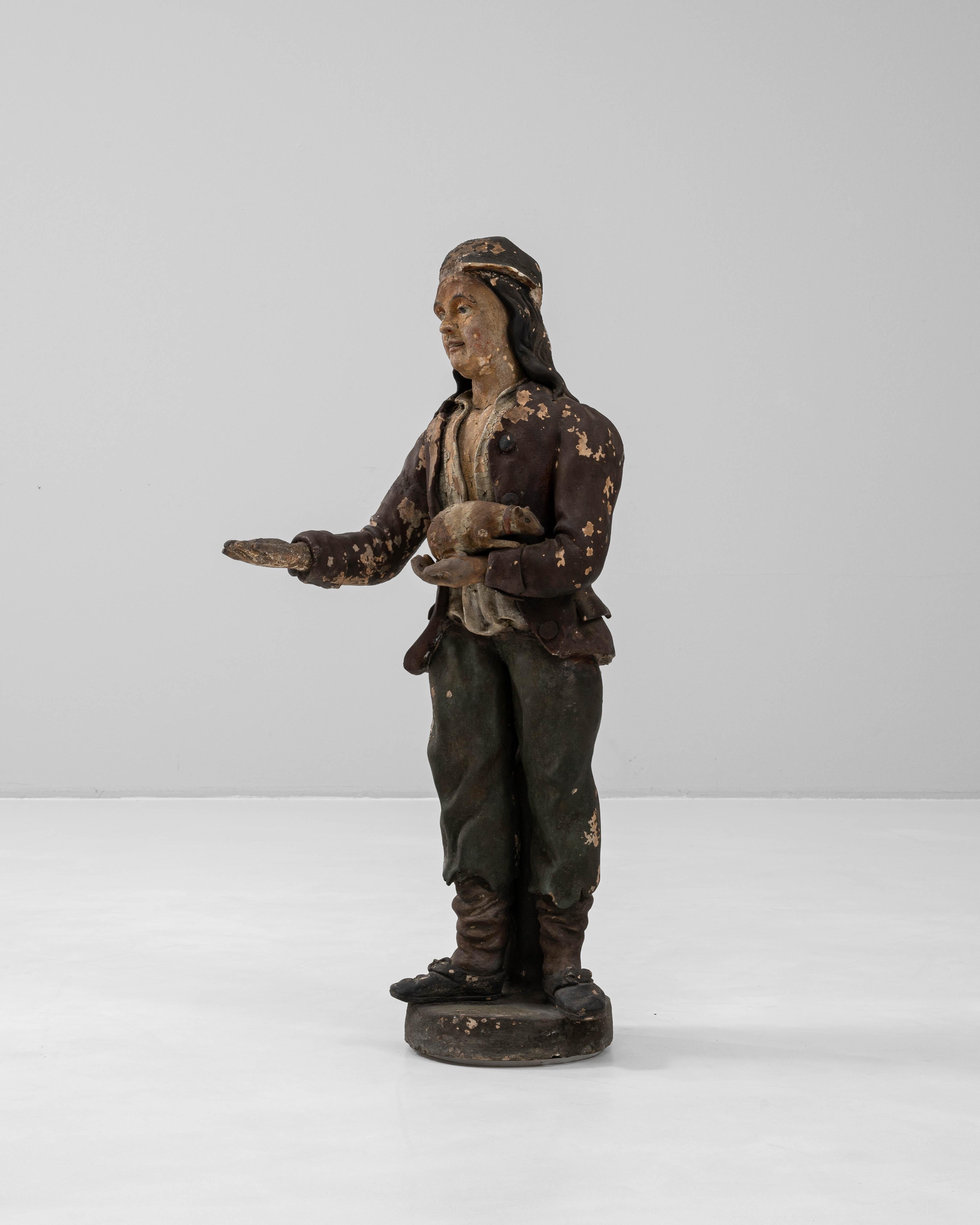 Esta escultura francesa de escayola del siglo XIX presenta una figura ricamente expresiva que sostiene una rata, un detalle inusual y posiblemente simbólico que añade intriga a su narrativa. La figura, vestida con un atuendo rústico con pañuelo y