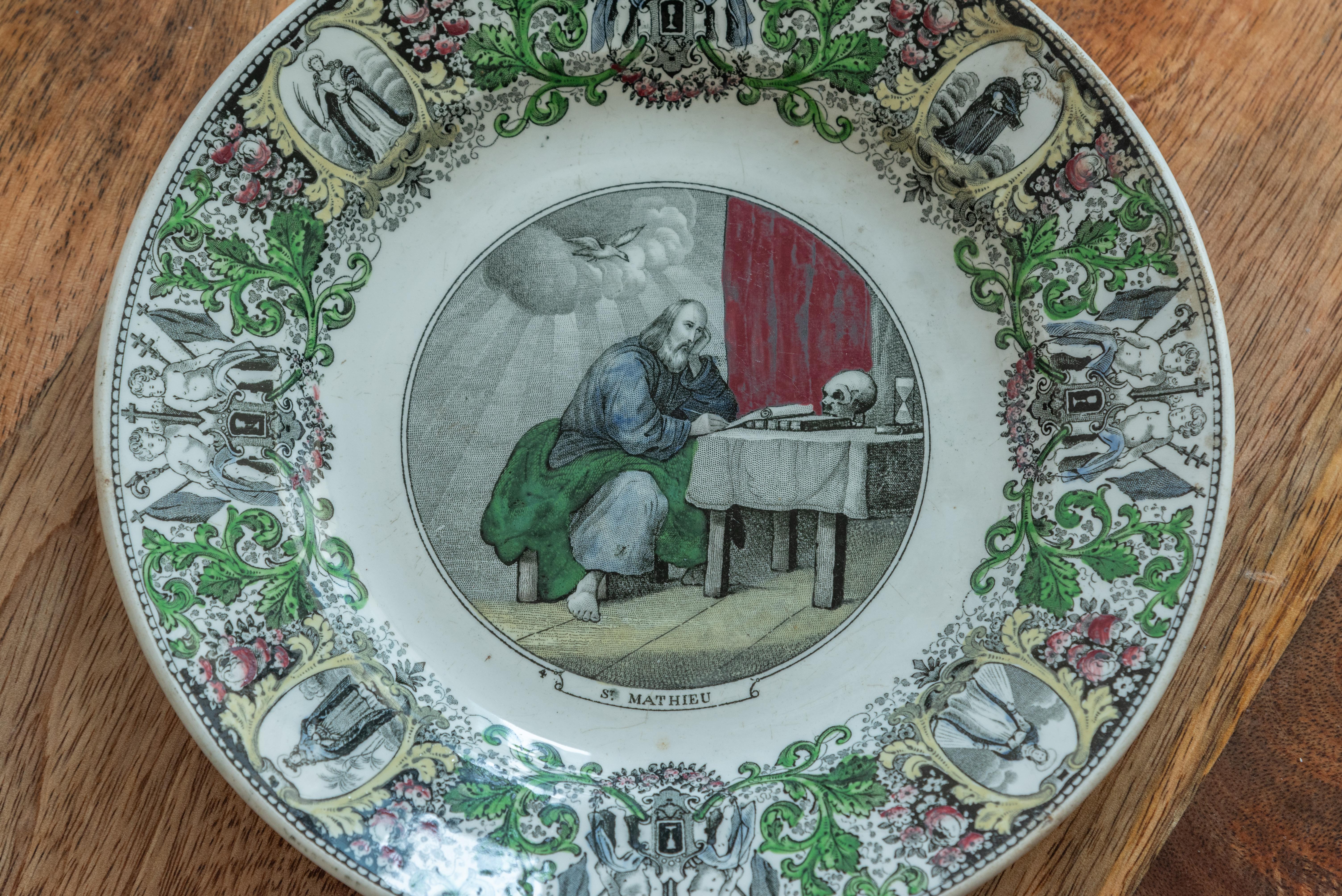 Step into the captivating world of 19th Century French Plates by Creil et Montereau, and be mesmerized by this exquisite plate featuring a captivating portrayal of St. Mathieu, the apostle, writing scripture. Crafted with meticulous attention to