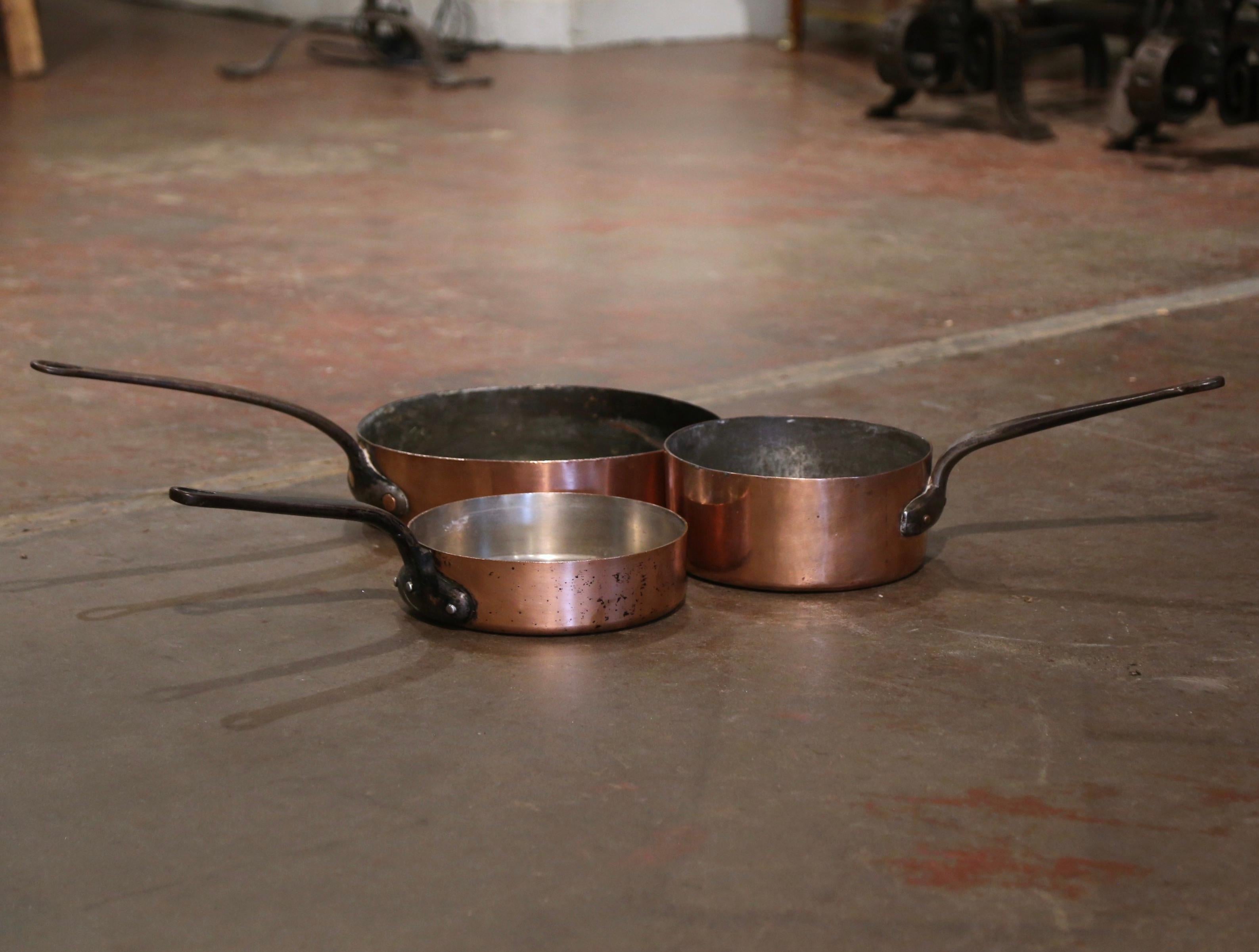 This set of round antique pans, were crafted in France, circa 1860. Made of copper with a large forged iron handle attached with rivets, these country kitchen essentials could still be used for cooking. The pots are in excellent condition, and each