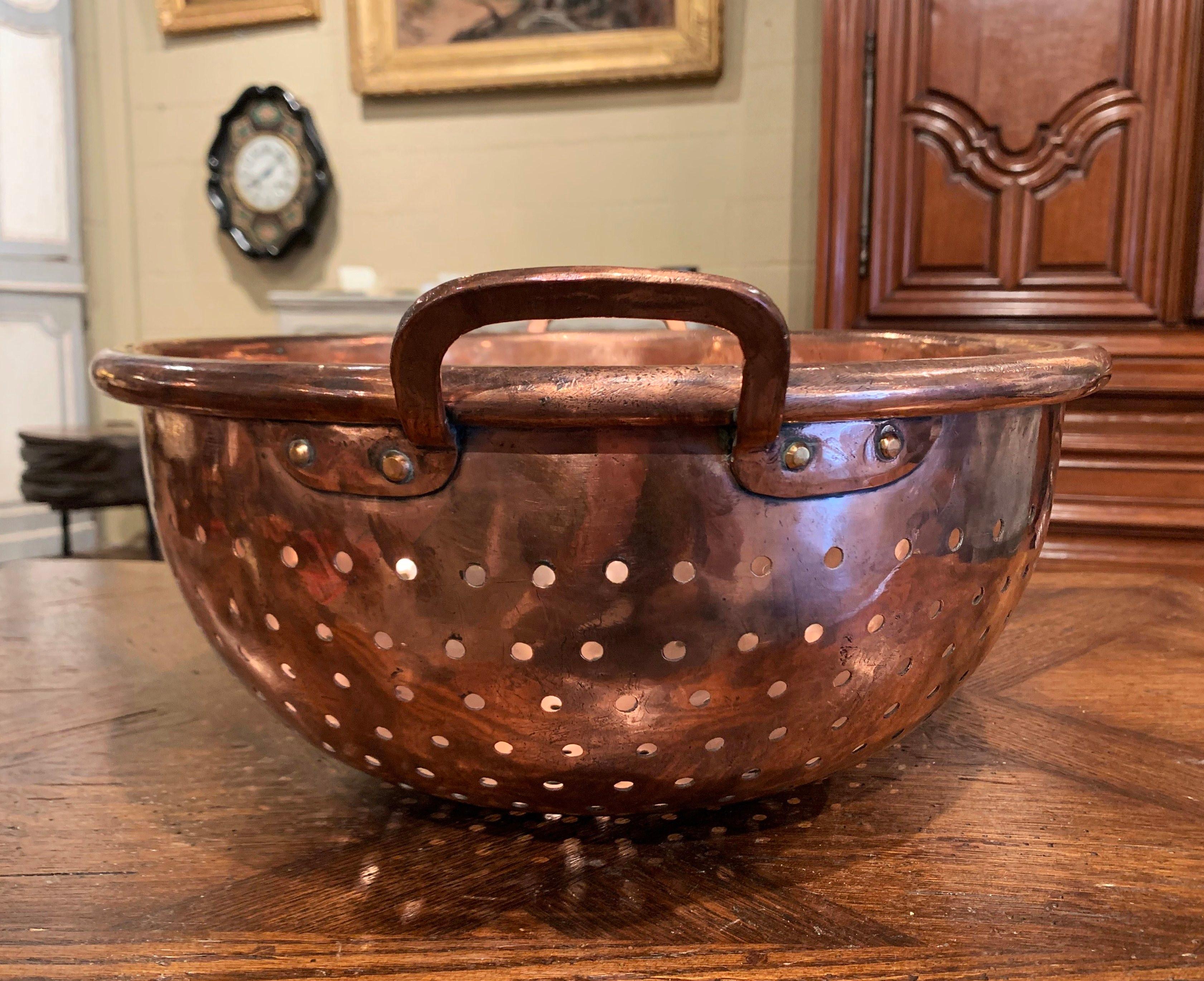 Decorate a kitchen island or cabinets with this elegant round bowl; crafted in Northern France, circa 1870, the circular copper colender bowl with rounded rim is embellished with side handles attached with rivets. The large dish is in excellent