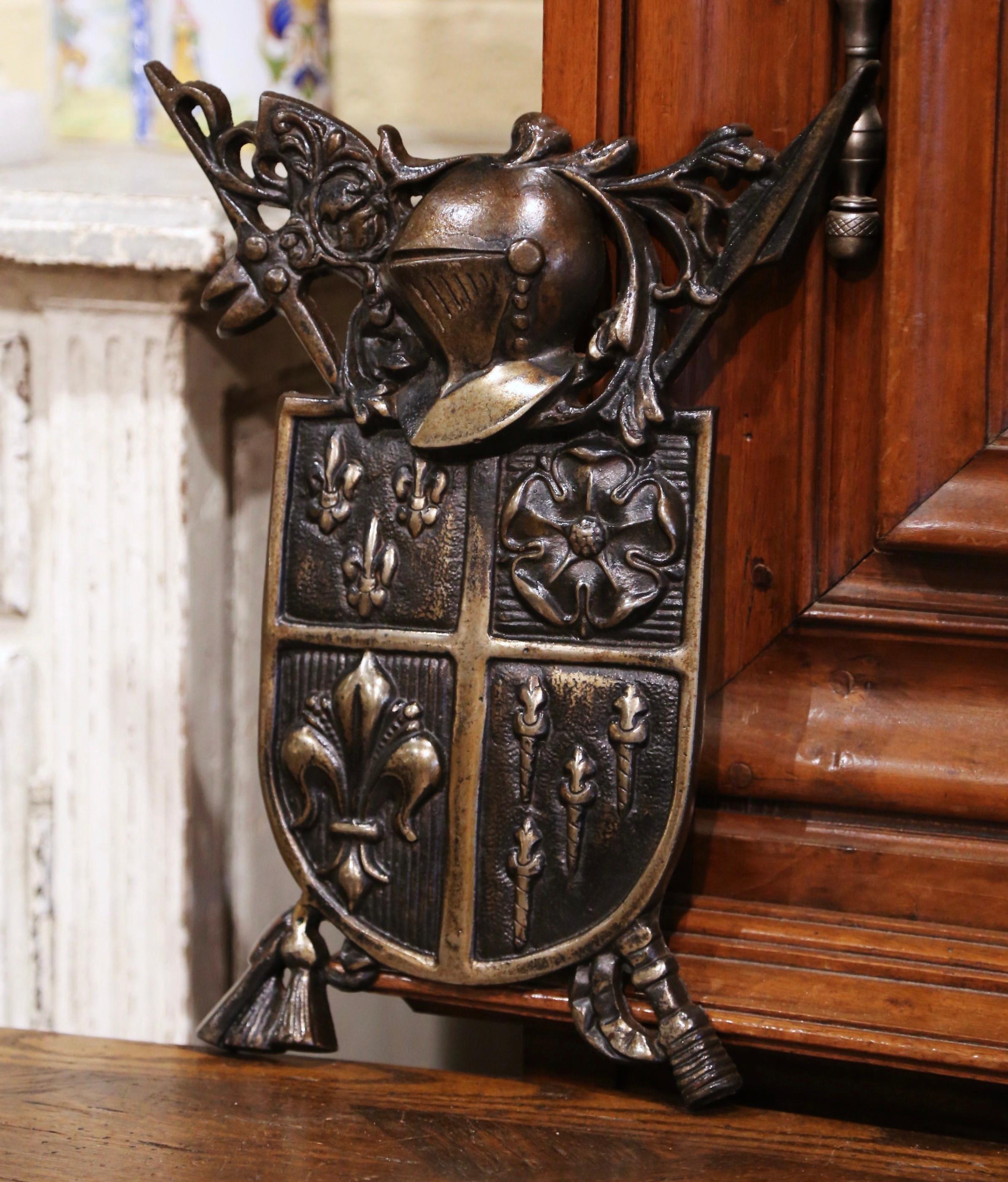 This antique heraldic carved coat of arms was crafted in France circa 1880; the crest, topped with a helmet, crossed spear and battle axe, features a center blason decorated with Fleur-de-Lis, torch and rose flower motifs. The wall emblem is in